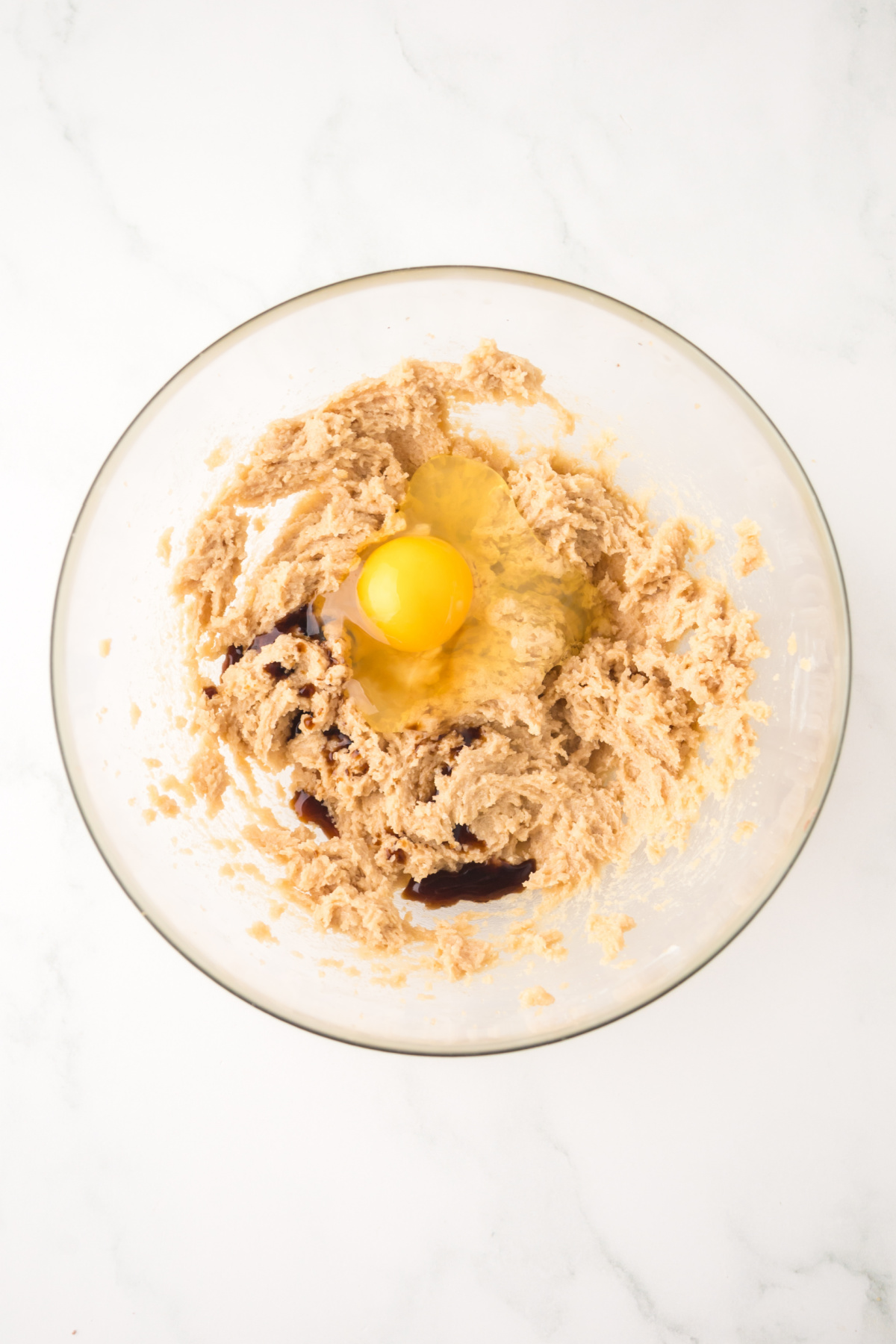 Butter, sugar, egg and vanilla in a bowl being mixed.