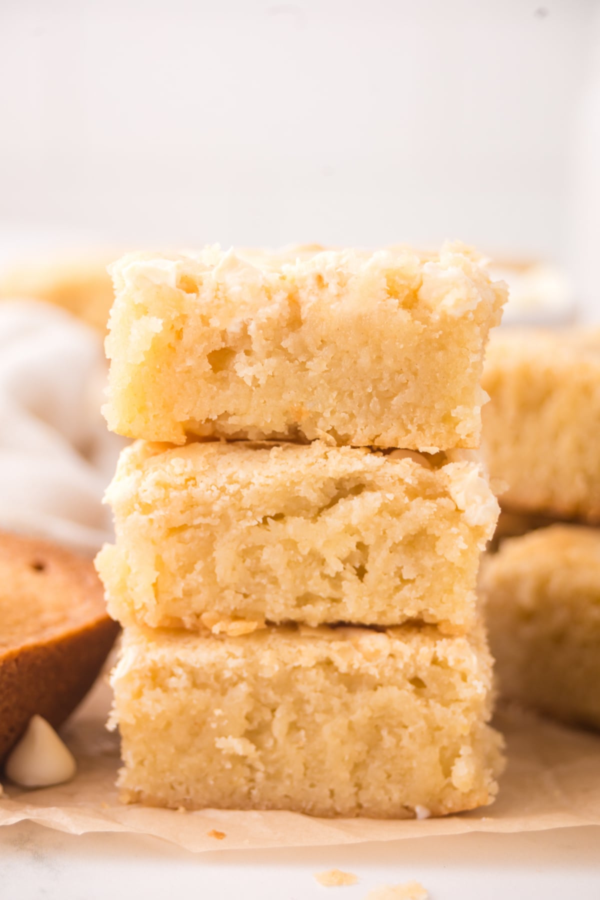 A stack of white chocolate brownies on parchment paper.