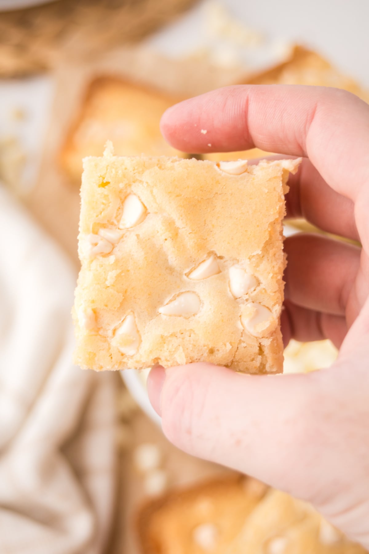 A hand holding up a white brownie square in the air.