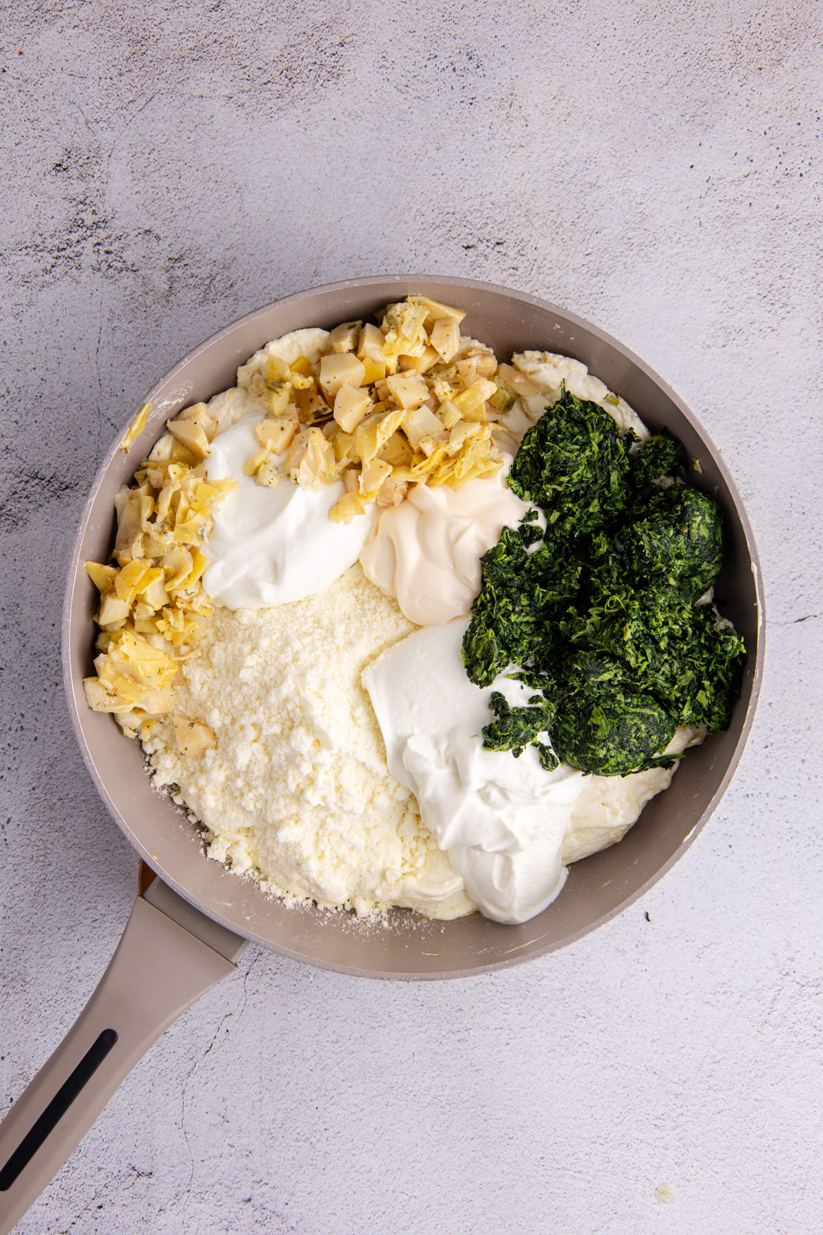 Artichokes, spinach, Greek yogurt, parmesan cheese, mayonnaise and sour cream added to the skillet.
