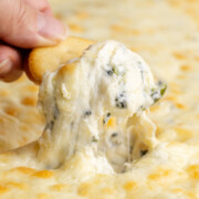 A cracker scooping out some healthy spinach artichoke dip.
