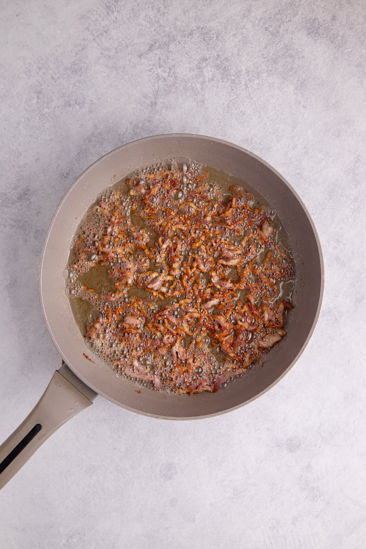 Bacon cooking in a skillet.