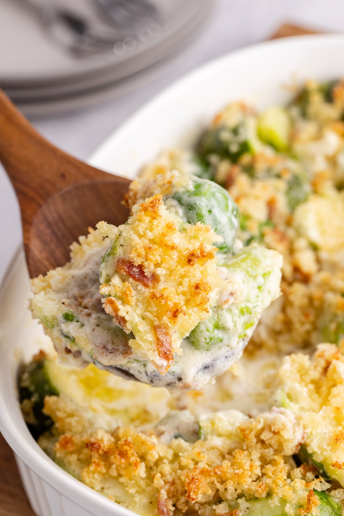 Spooned casserole with Brussels sprouts being held up in the air.