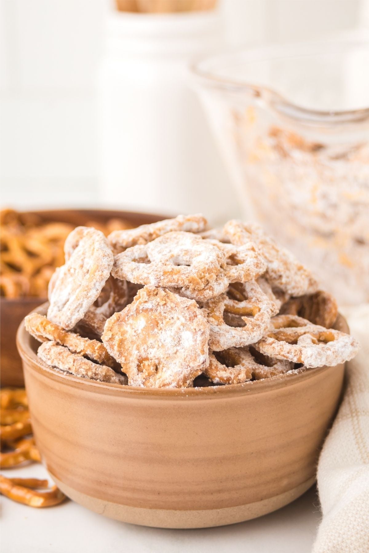 A bowl of homemade pretzels coated in sweet butterscotch and powdered sugar on a table.
