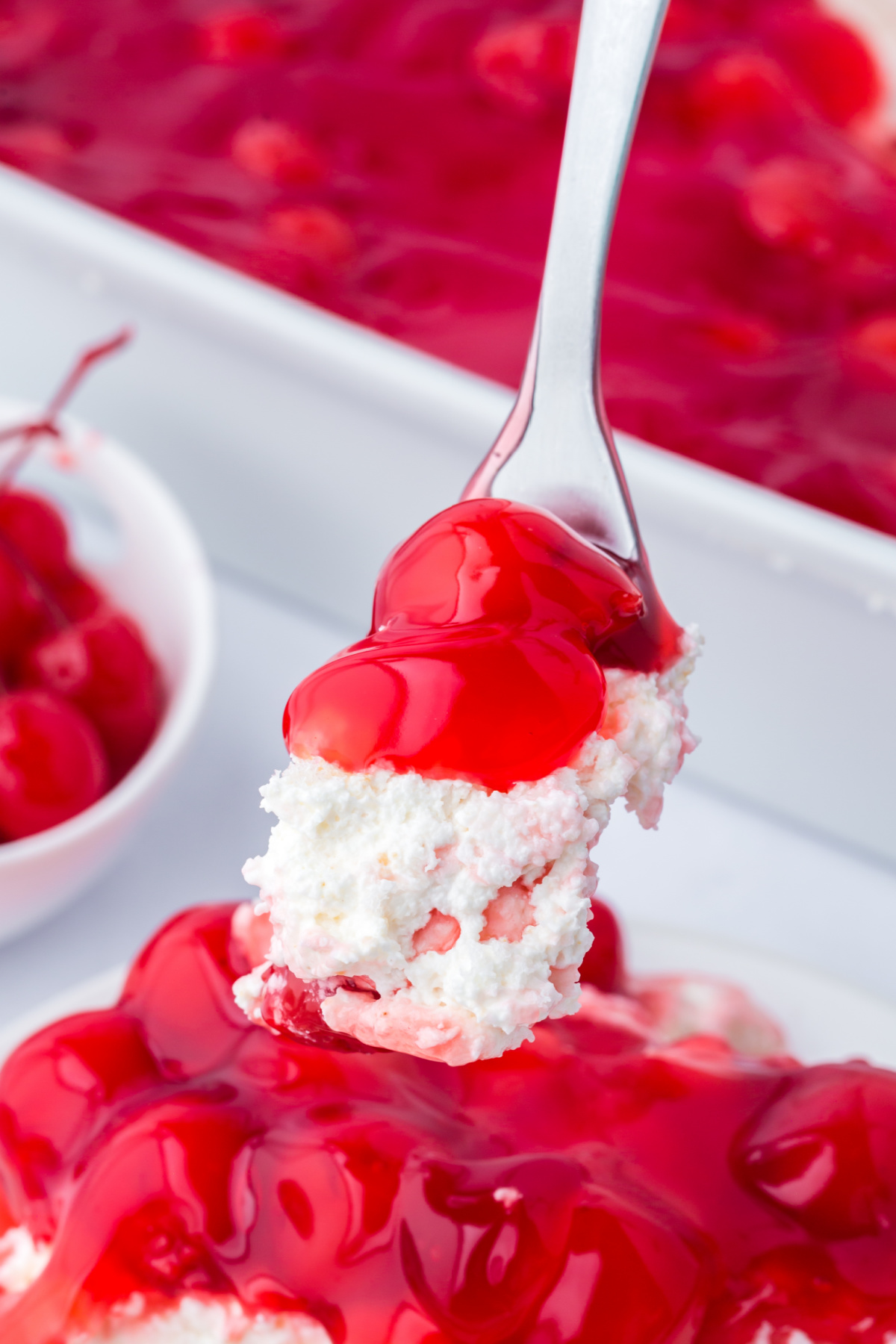 A fork taking some cherries in the snow dessert.