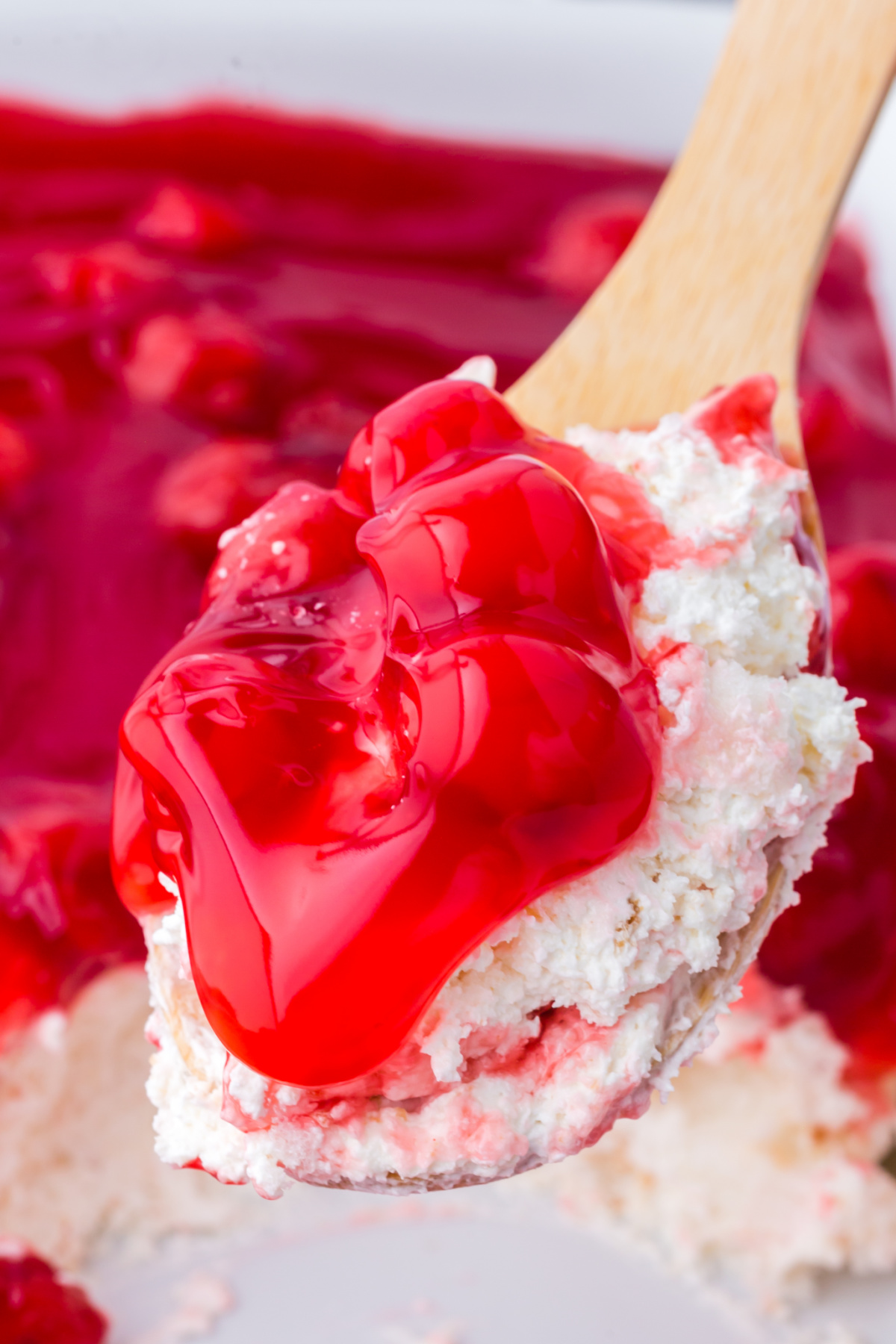 A wooden spoon scooping up some cherry dessert.