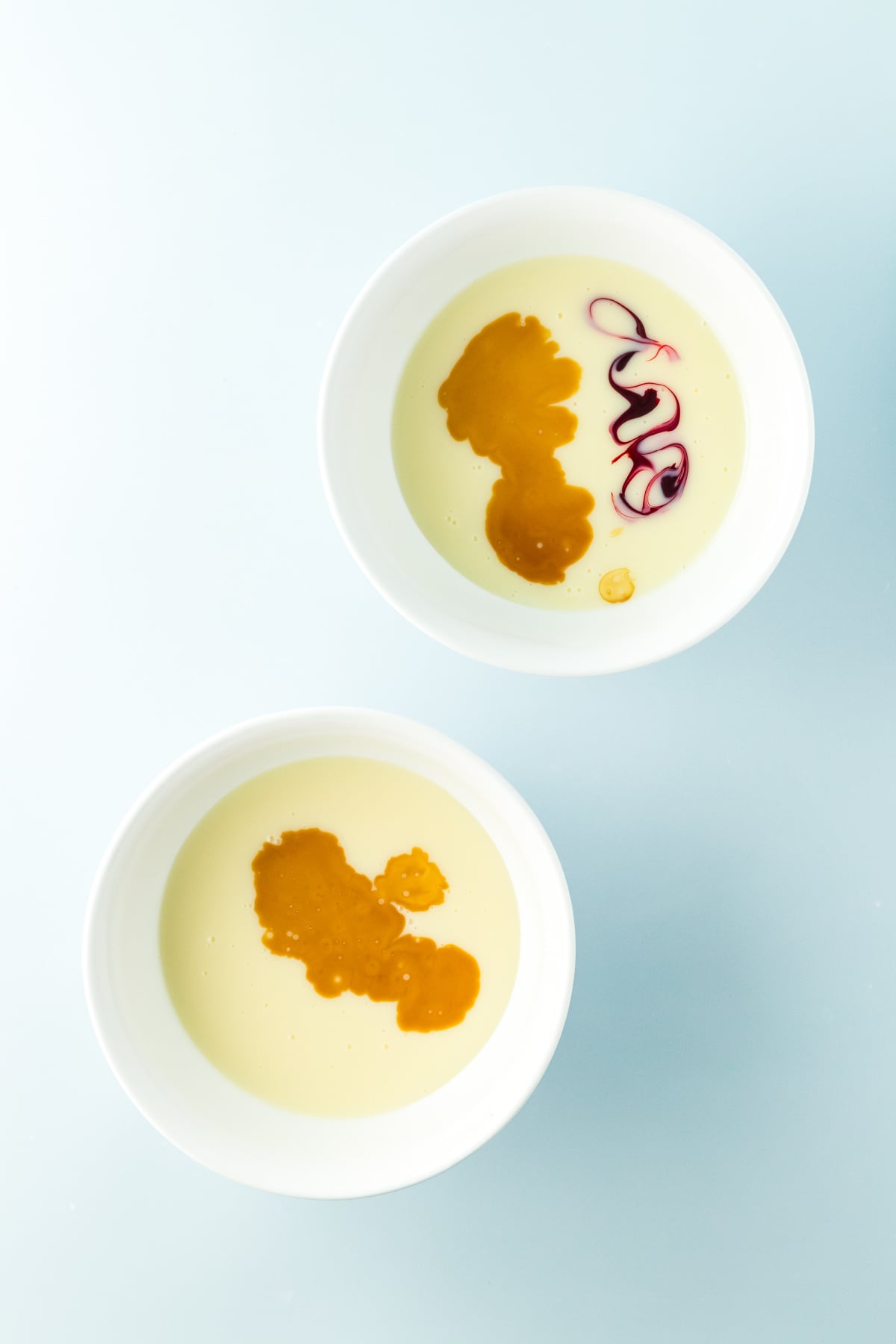 Two bowls with sweetened condensed milk divided between them with food coloring.