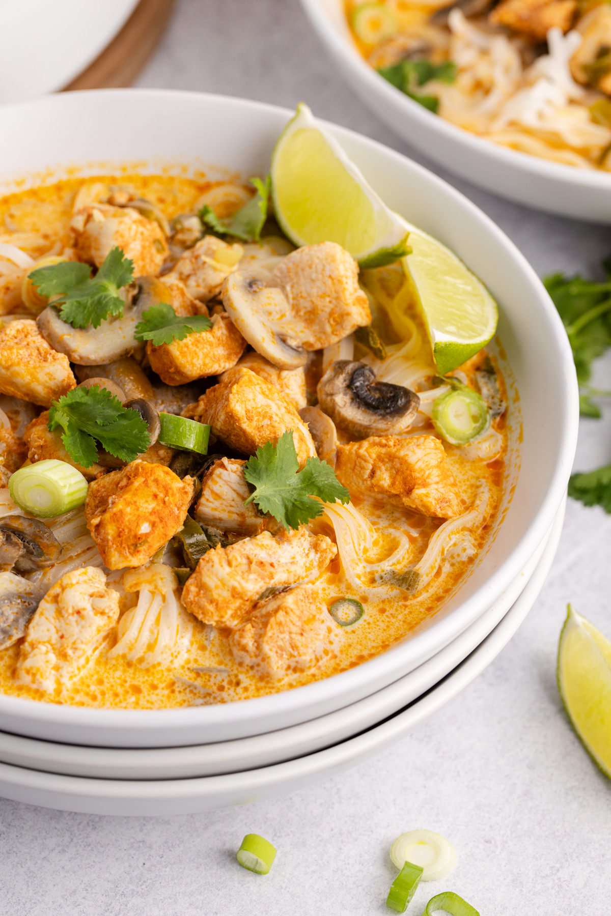 Chicken soup with mushrooms and a side of lime in a bowl.