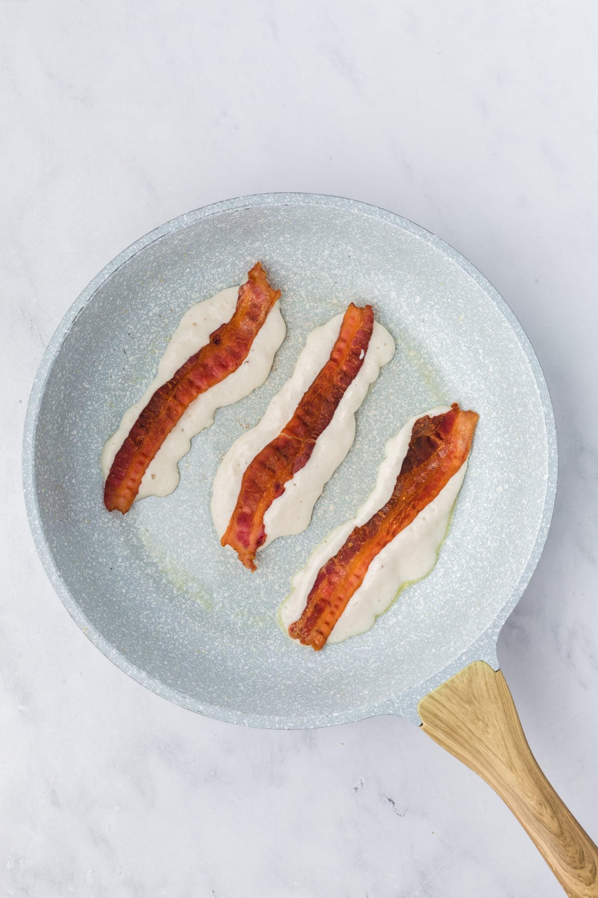A strip of bacon placed onto each strip of batter.