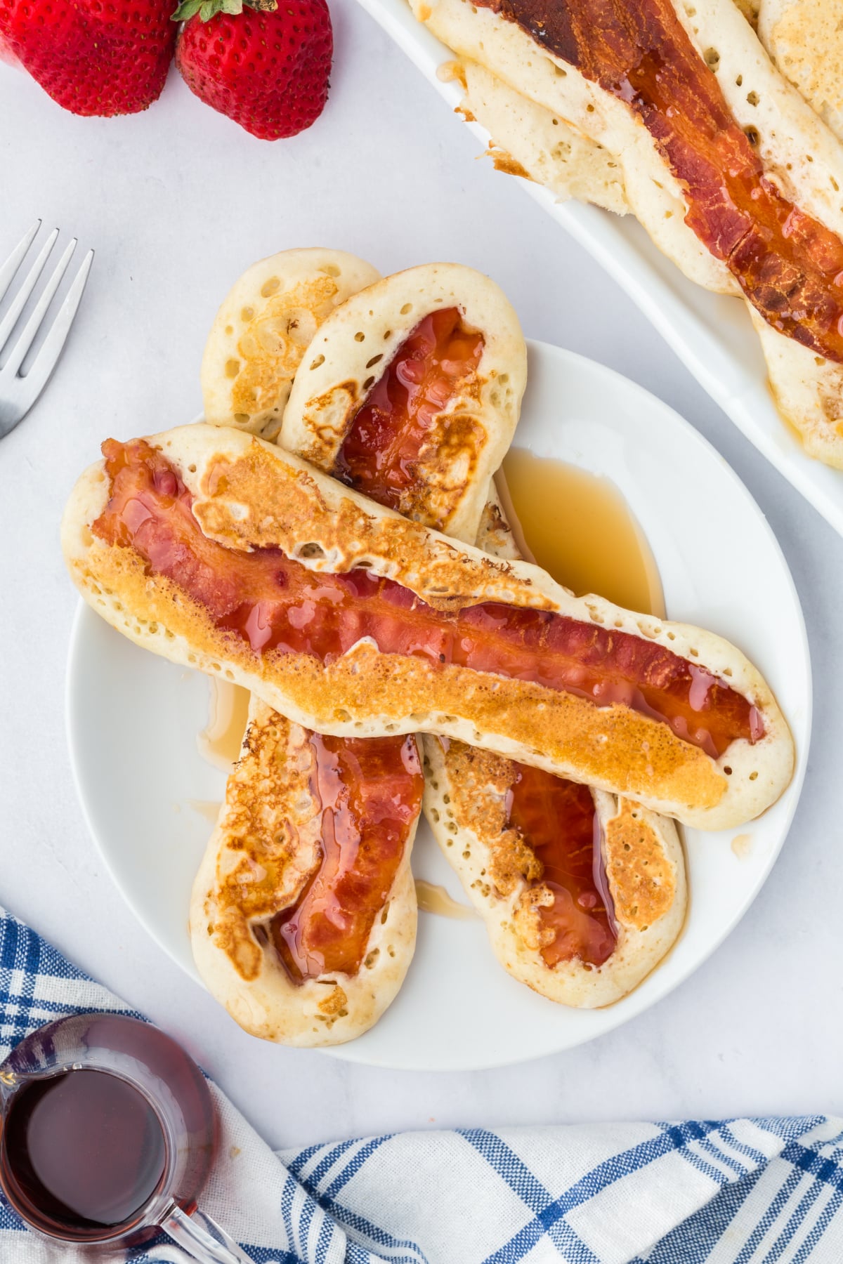 A plate with bacon dippers with syrup on top.