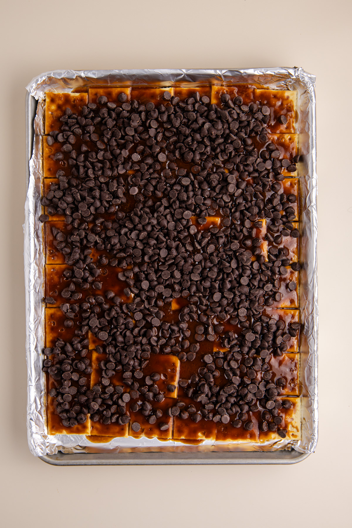 Caramel covered crackers with chocolate chips sprinkled all over them on rimmed baking sheet