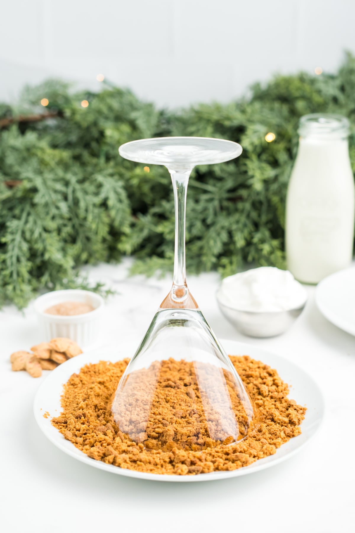 The rim of a martini glass being dipped in crushed cookies and syrup.