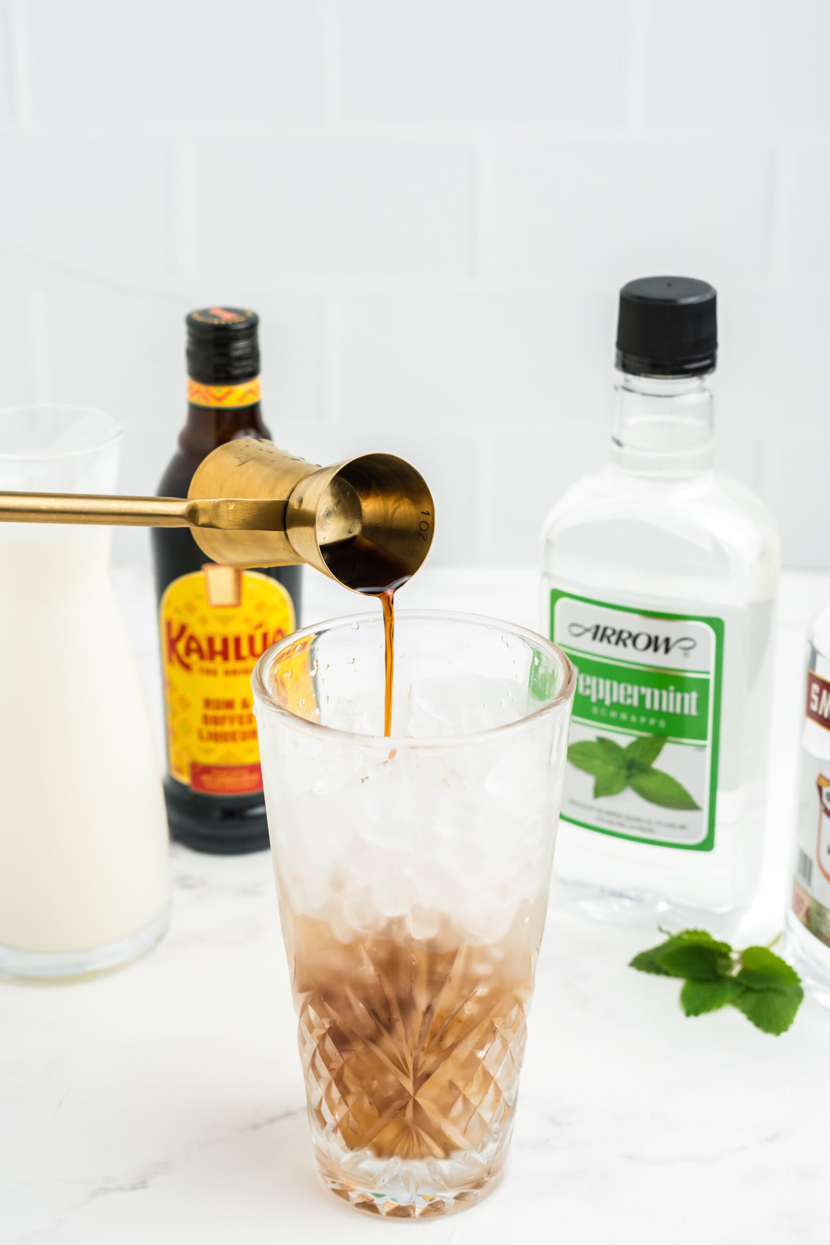 Vodka, coffee liqueur, and peppermint schnapps added to the cocktail shaker with ice.