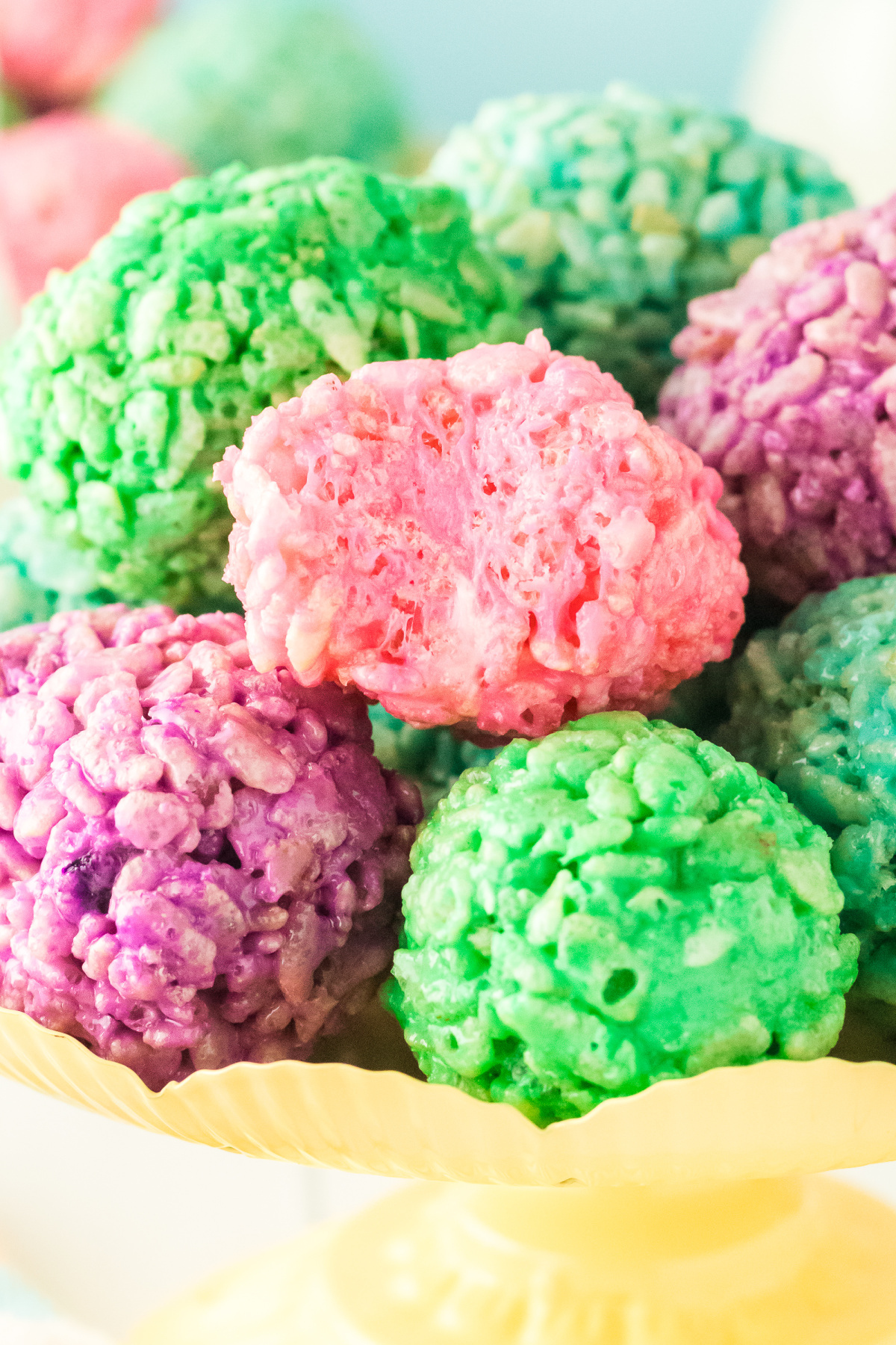 A bowl filled with rice krispie treats in the shape of eggs with a bite taken out of the top egg.