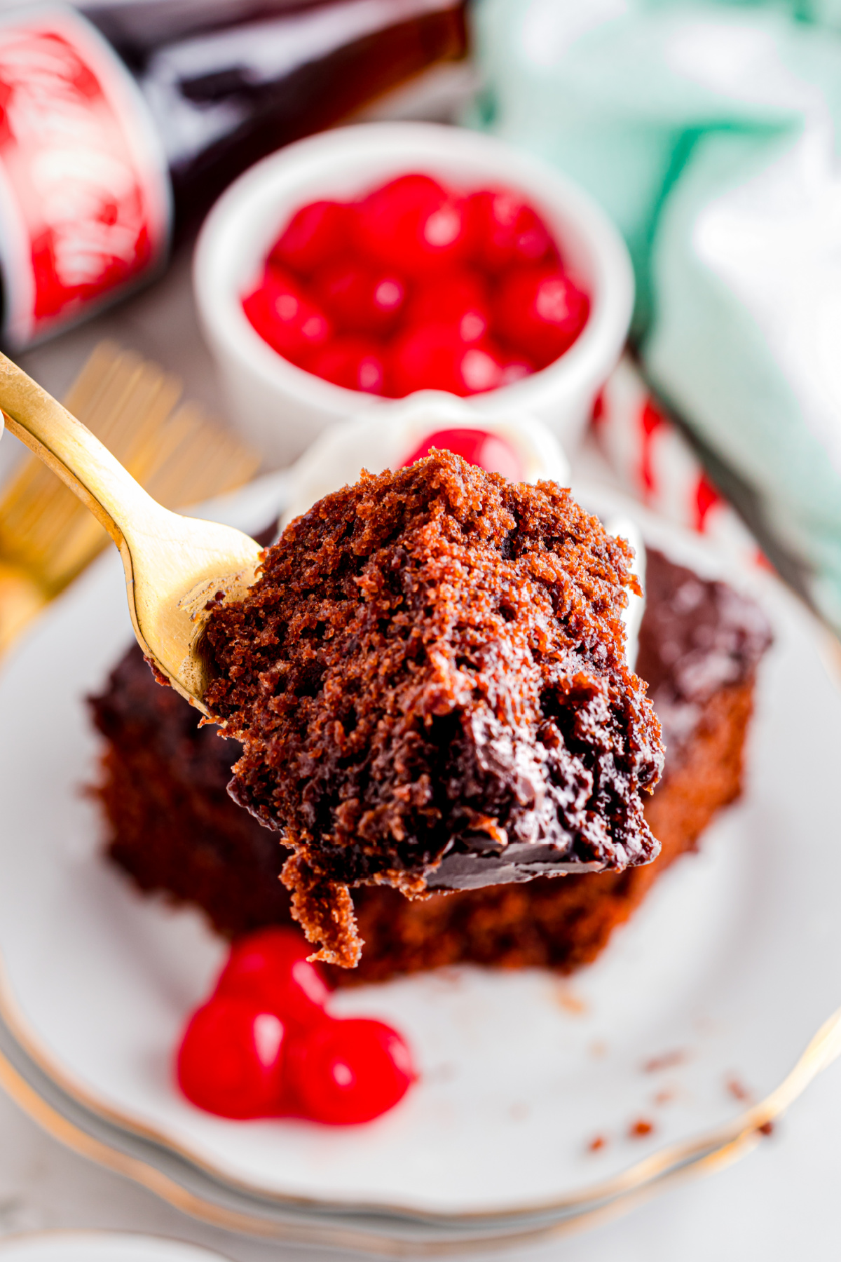 A piece of cake with coca cola in it being held up with a fork.