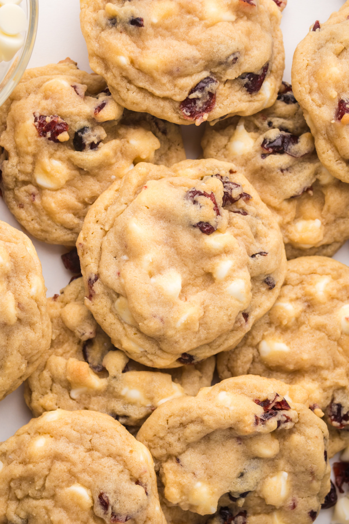 A pile of cookies with cranberries and white chocolate chips.