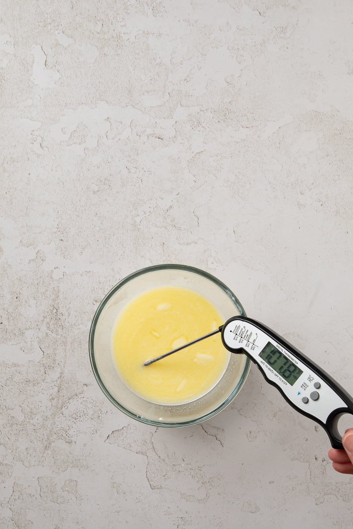 Milk and butter in a bowl with a thermometer in it.