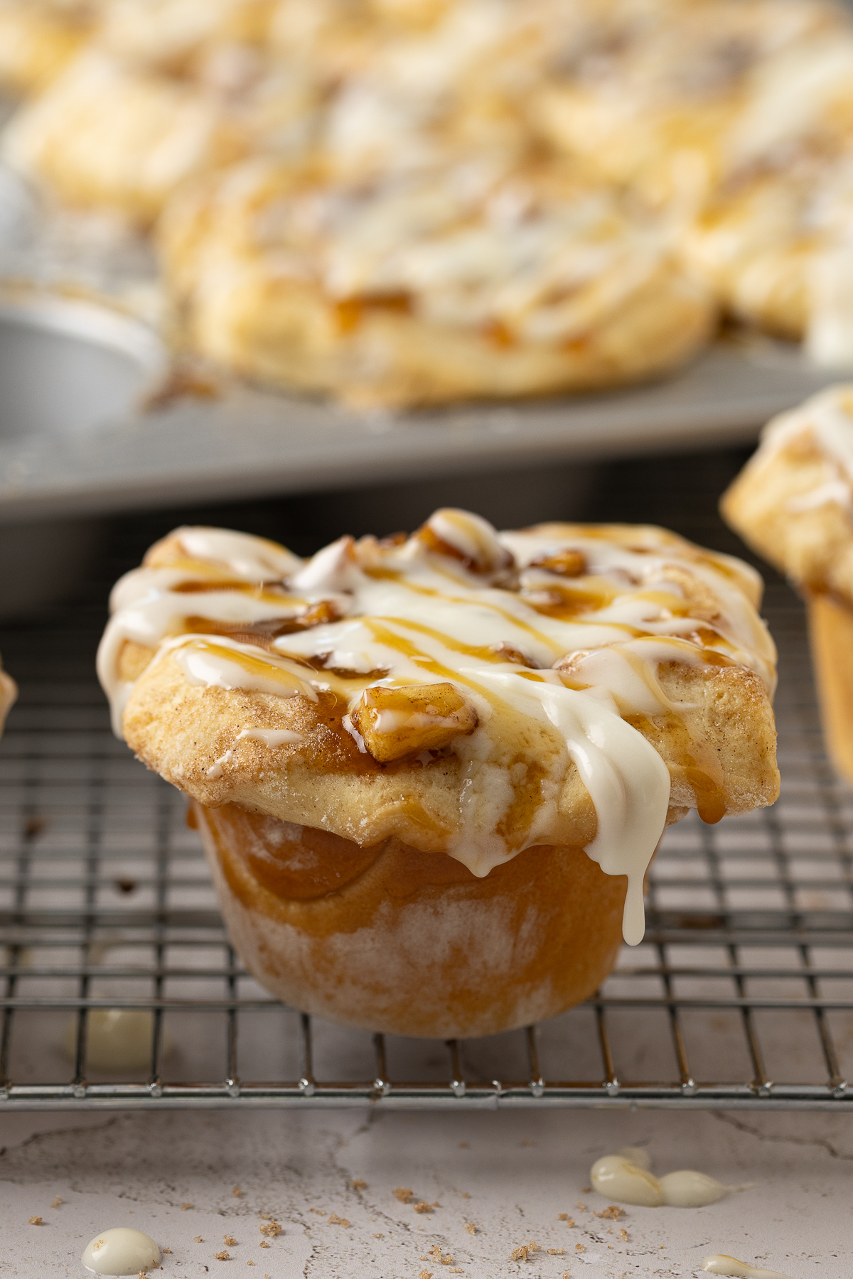 A muffin shaped apple pie with icing dripping off the top.
