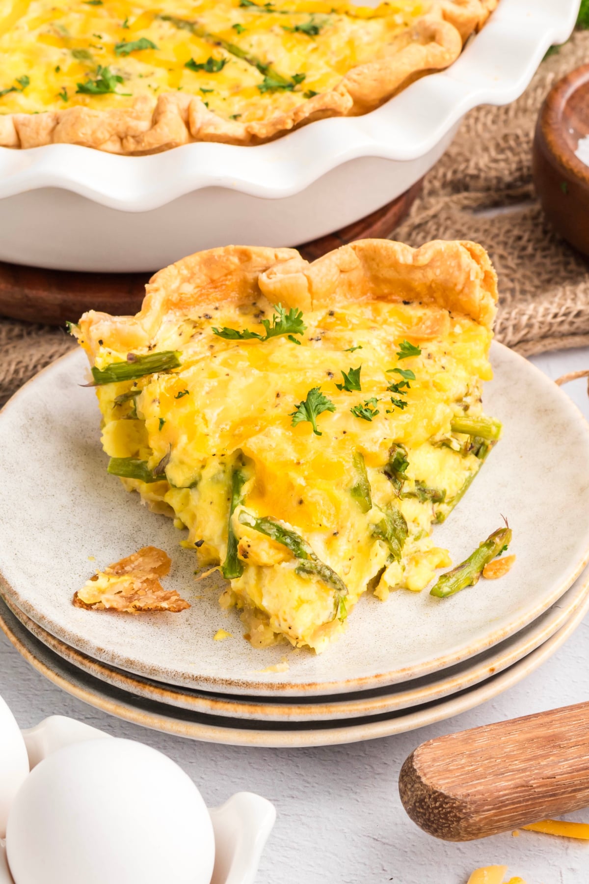 A slice of aspragus quiche on a plate with asparagus.
