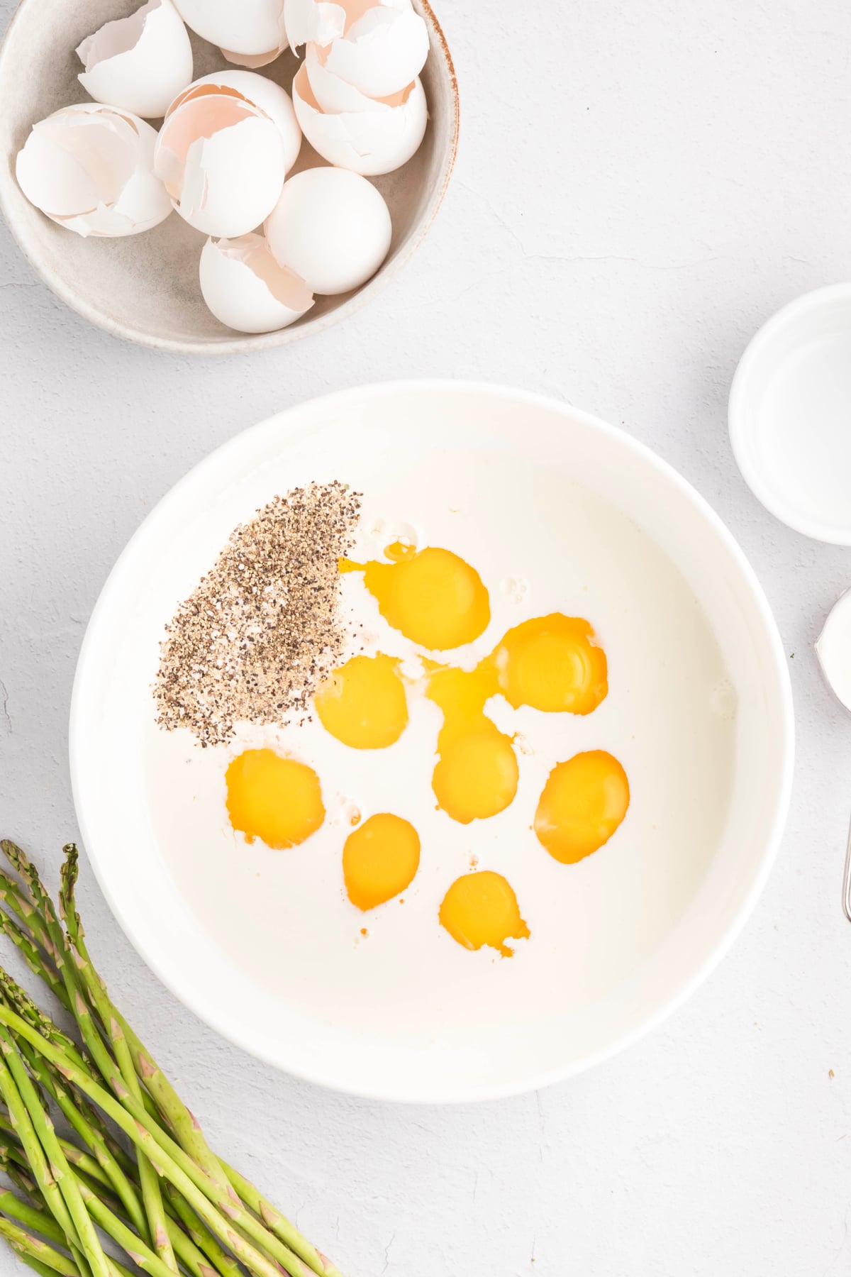 Eggs, milk, cream, salt, and pepper combined in a mixing bowl