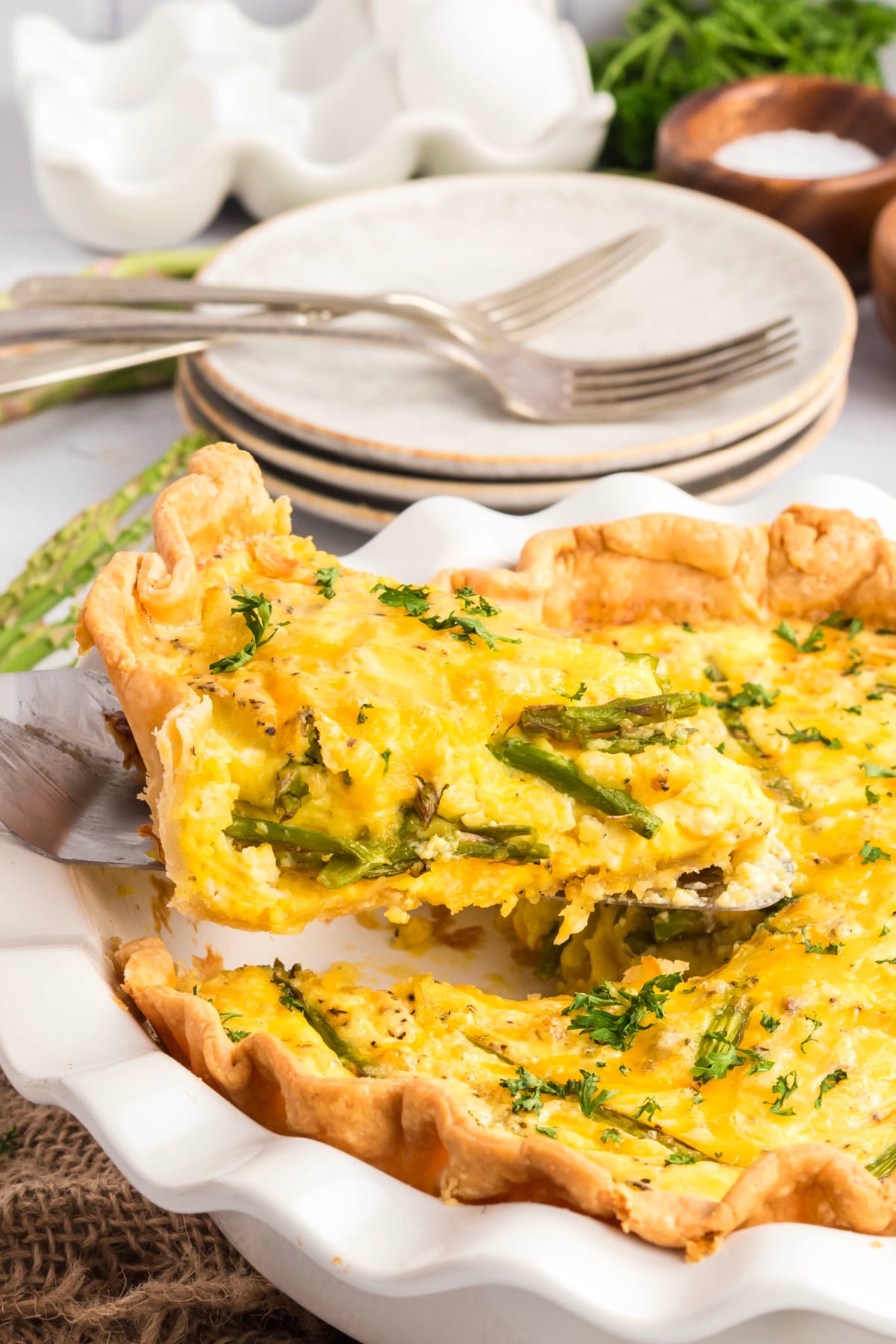 A slice of quiche being taken out of the pie dish.