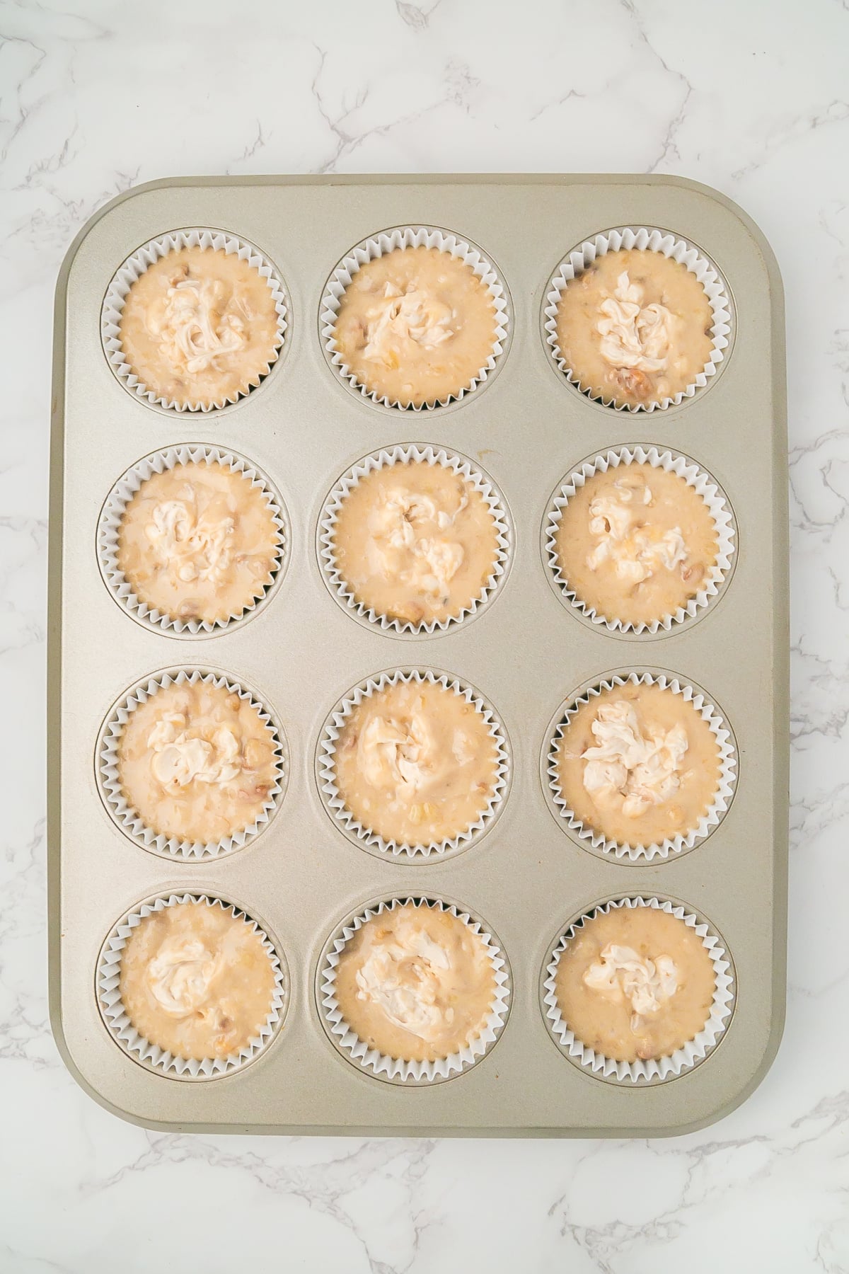 Cream cheese is added to each muffin and swirled with a butter knife.