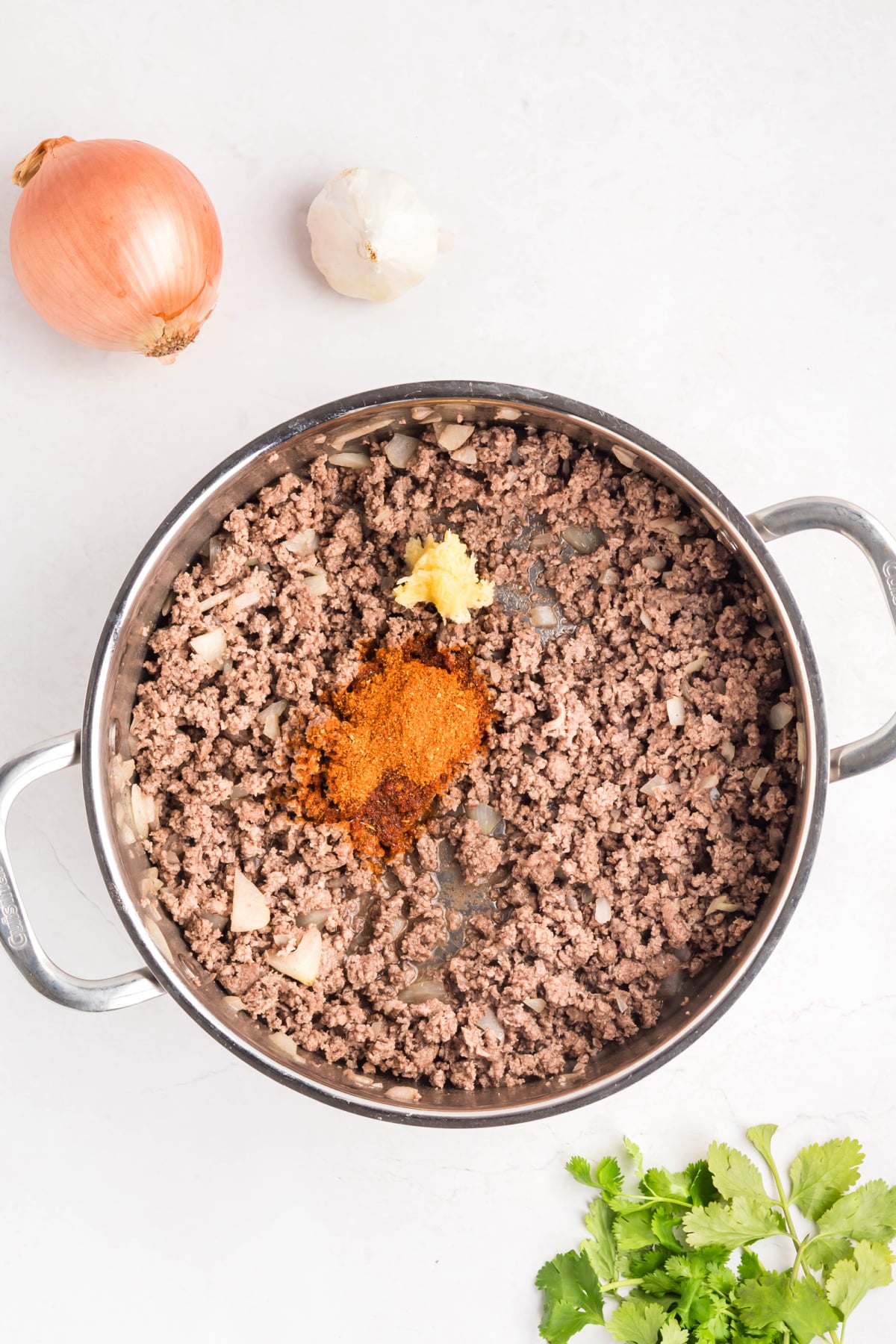 Ground beef and onions mixed in a large skillet.