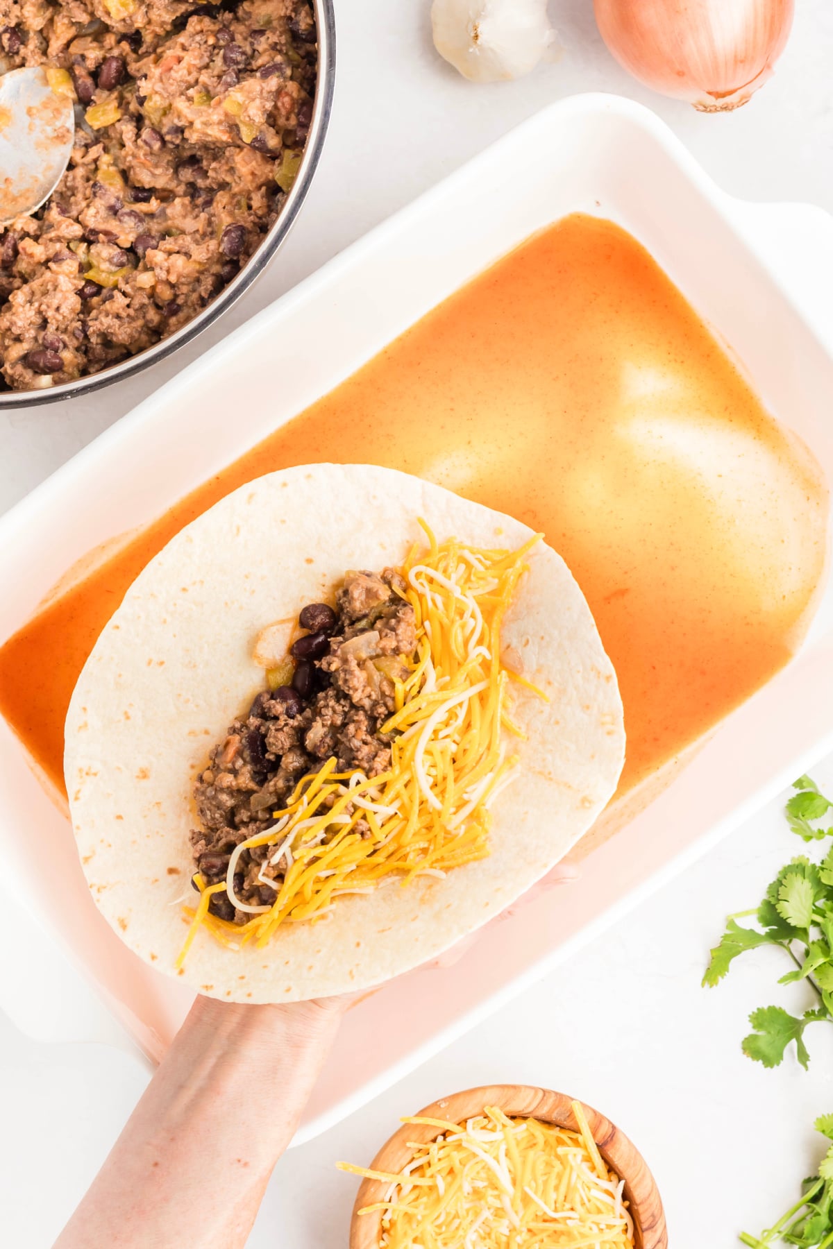 Meat mixture and some shredded cheese in a tortilla.