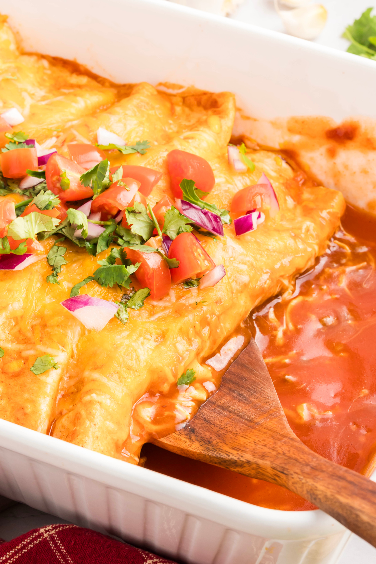 A wooden spoon scooping out a ground beef enchilada.