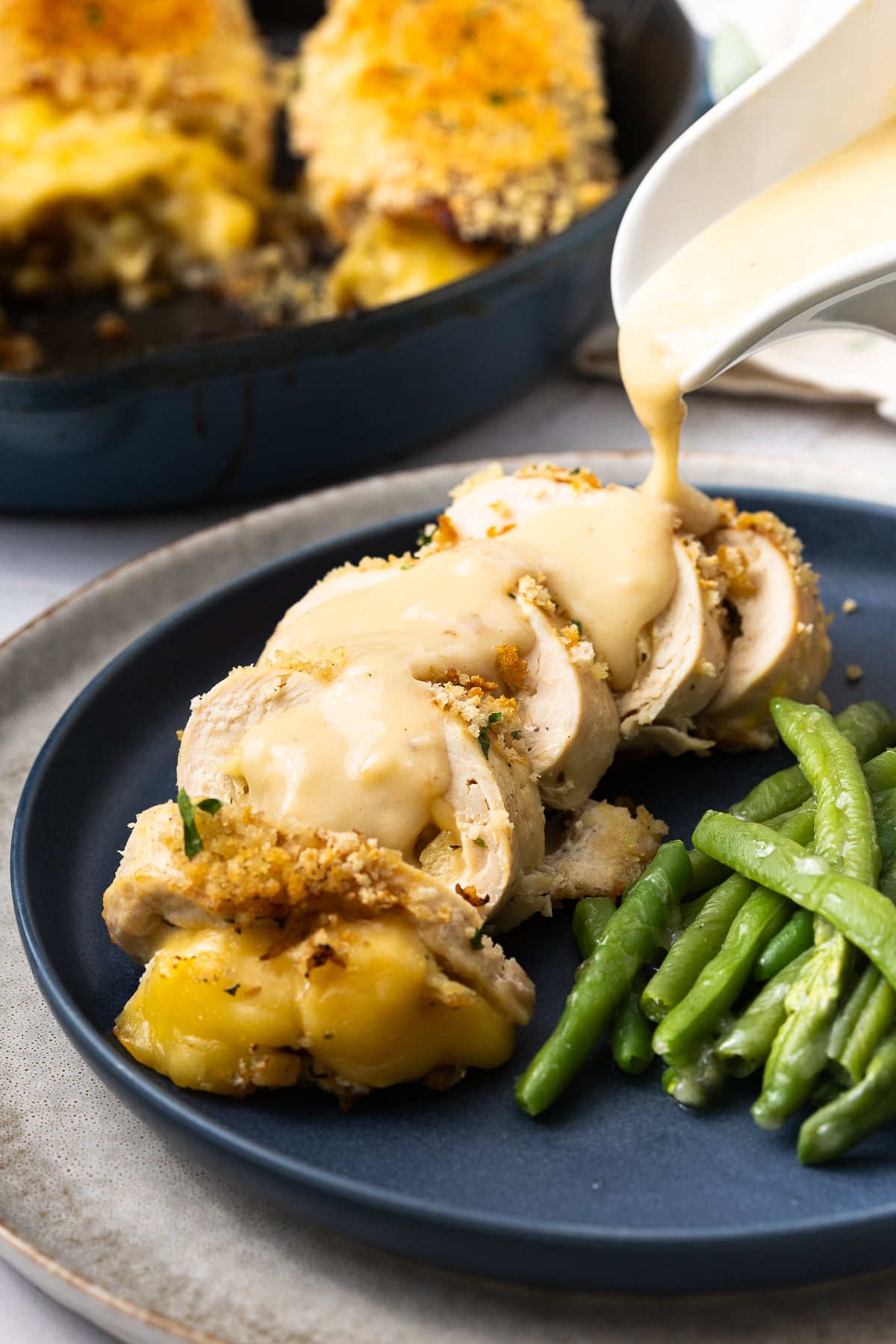 Gravy being poured over top of the finished stuffed chicken breast.