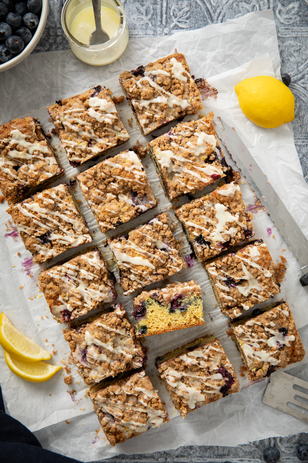 Sour cream blueberry cake sliced into pieces on parchement paper.