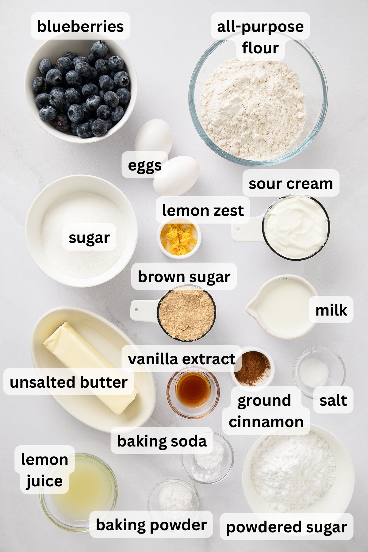 Ingredients to make blueberry sour cream cake in bowls on a table.