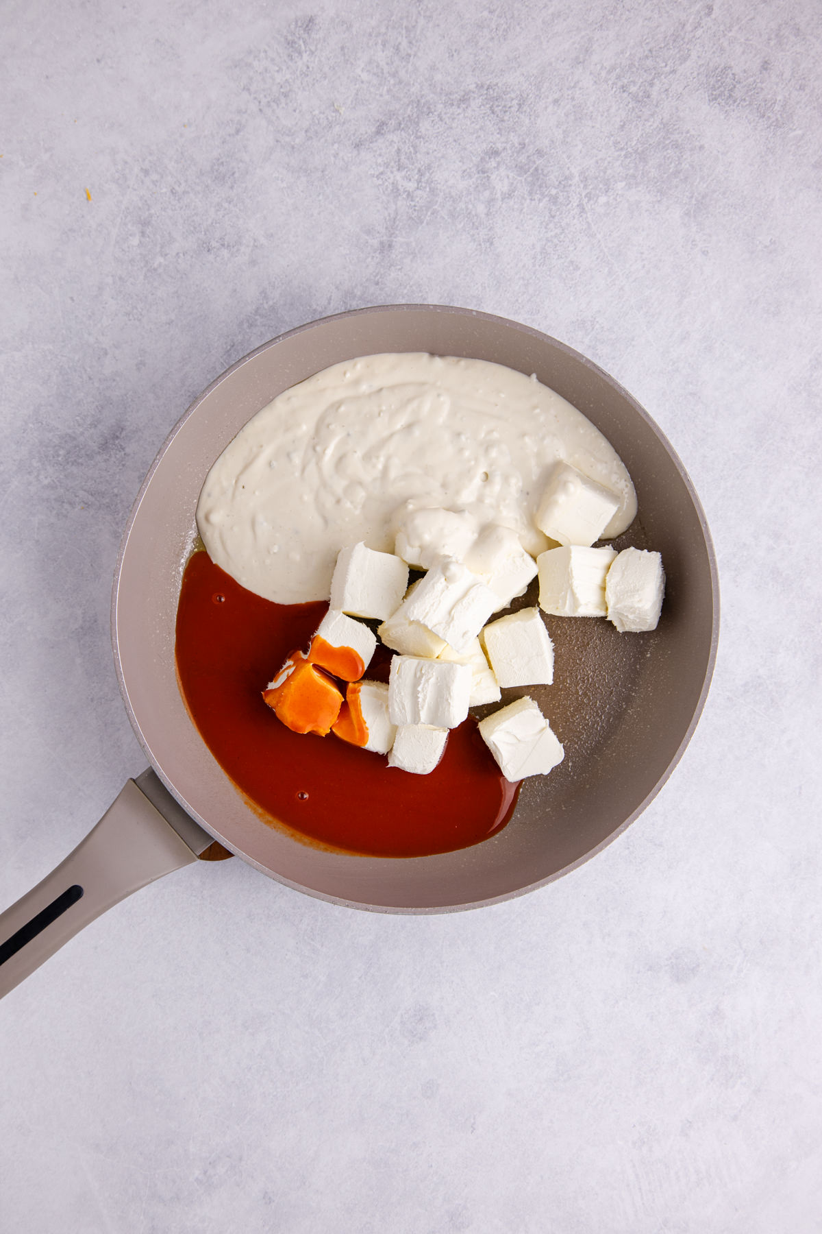 Buffalo sauce, cream cheese, and blue cheese dressing in a saucepan.