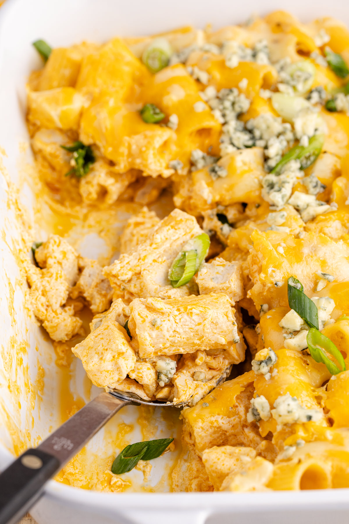 A large spoon scooping out some casserole with chicken.