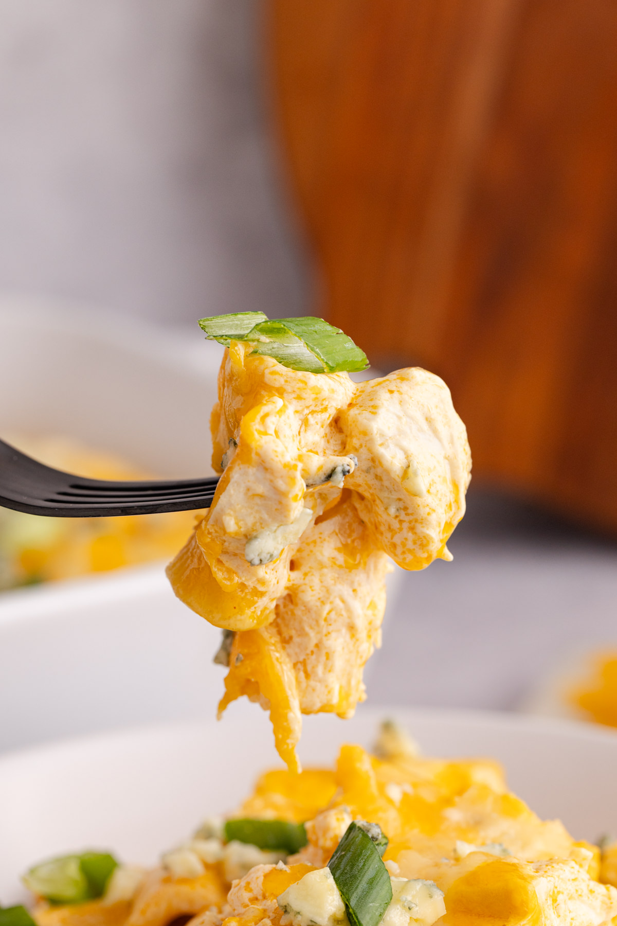 Some buffalo chicken held up in the air with a fork.