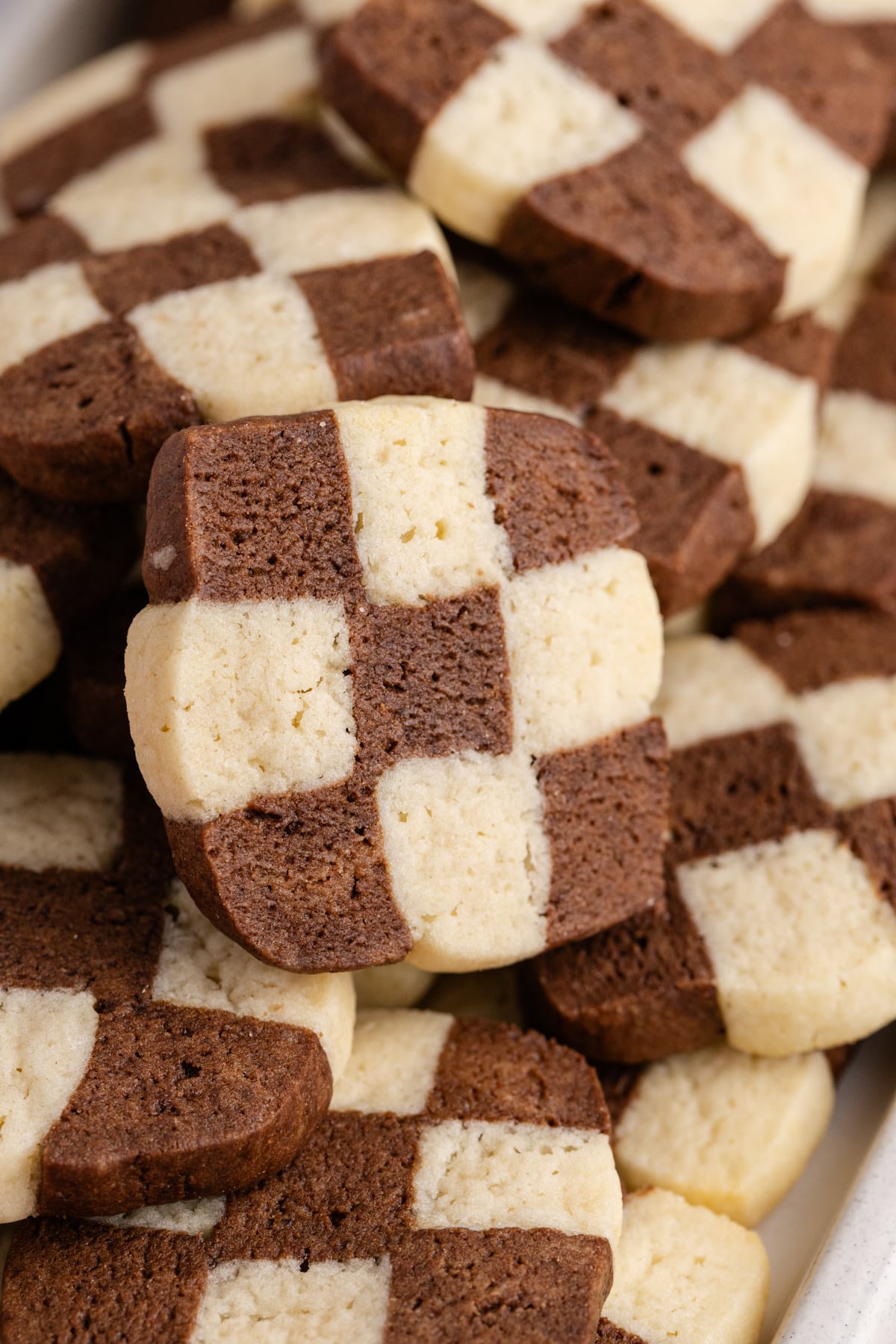 A pile of chocolate and vanilla cookies in the shape of a checkerboard.