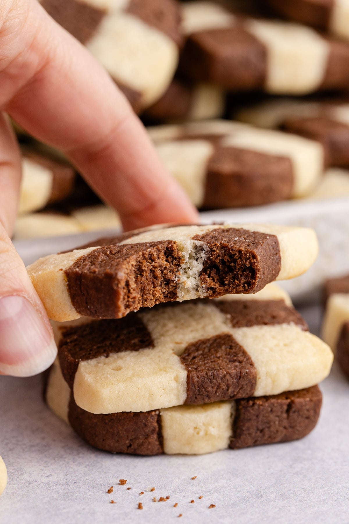 A cookie in the shape of a checkerboard stacked with a bite taken out of the top cookie.