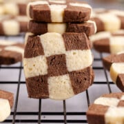 Checkerboard cookies standing upright against other cookies.