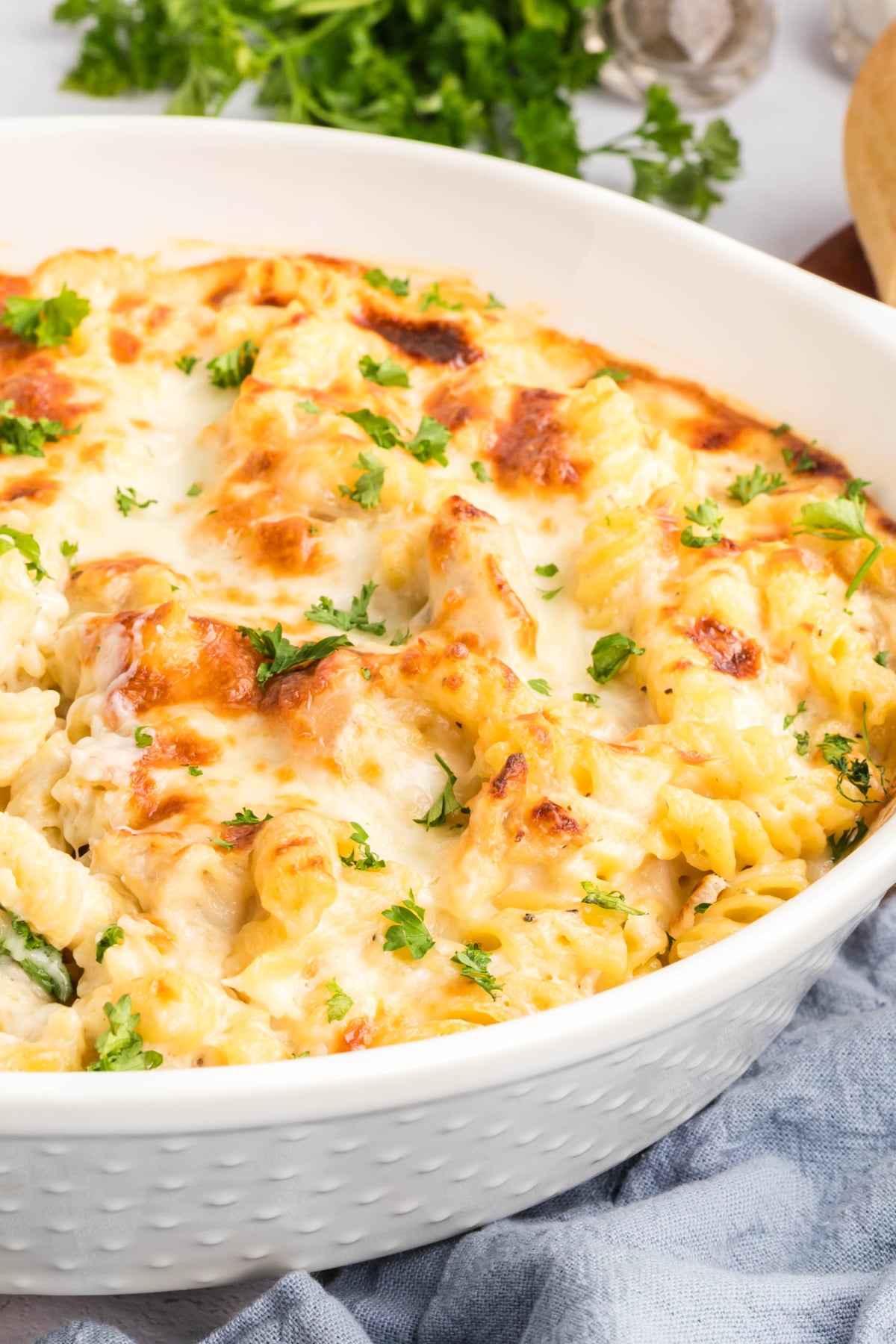 Chicken alfredo with pasta in a casserole dish garnished with parsley.