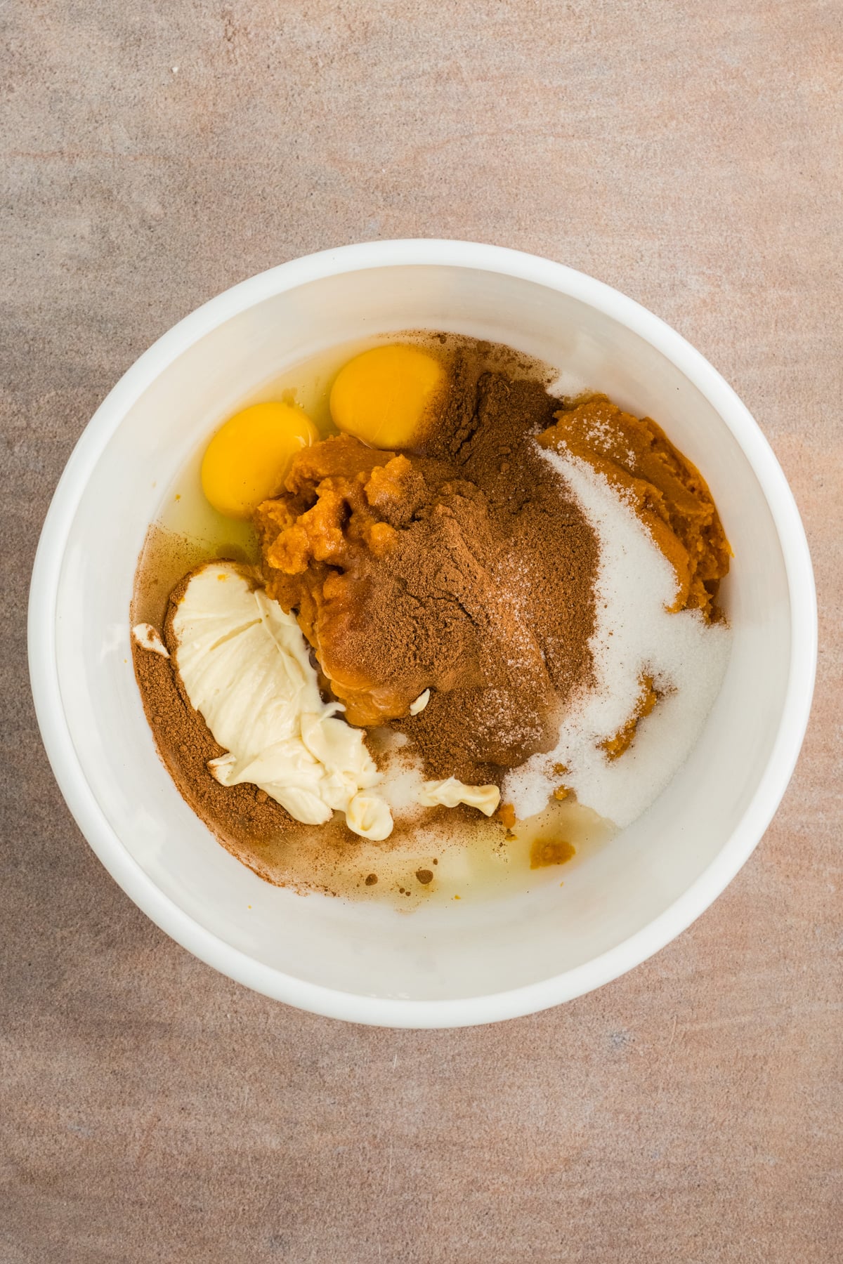 Pumpkin, eggs, sugar, and spices in a bowl.