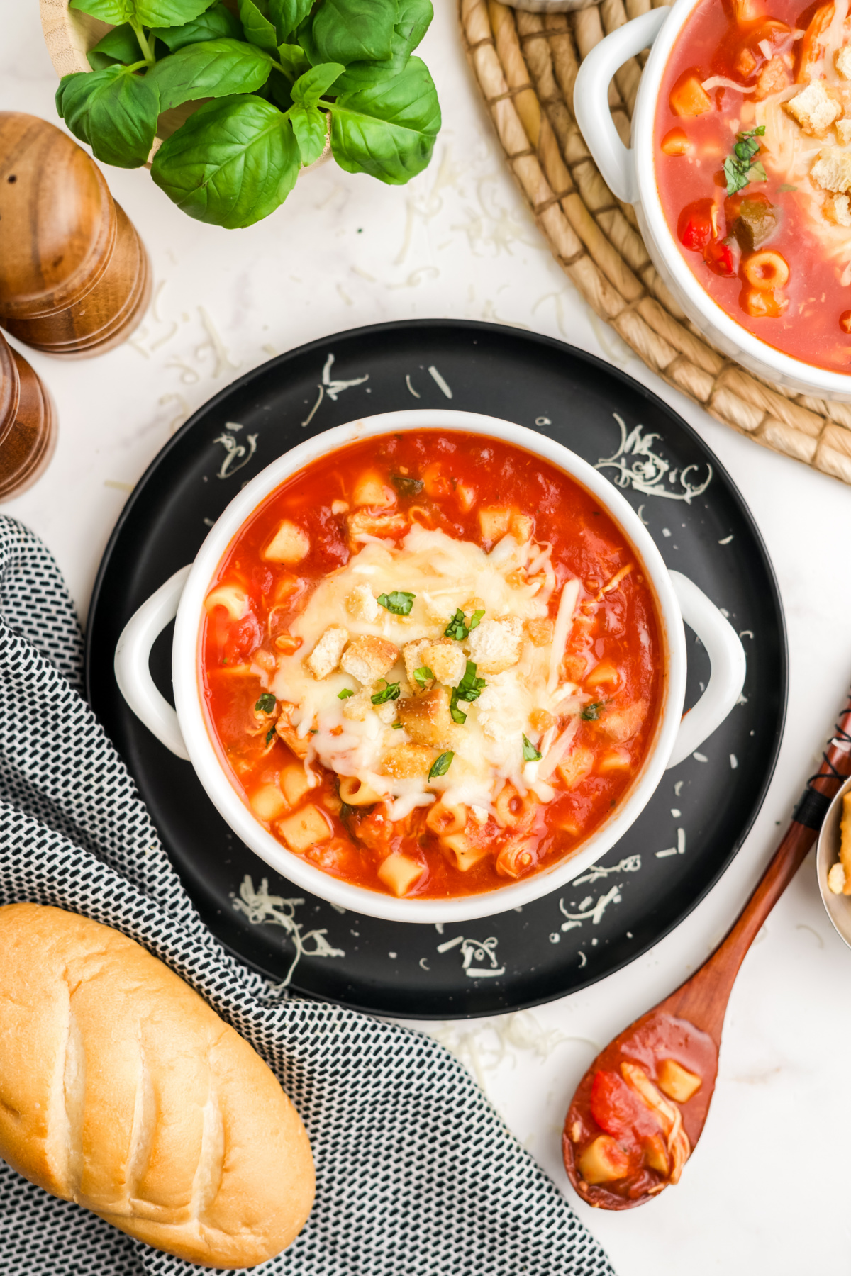 Chicken parmesan soup in a bowl on a plate.
