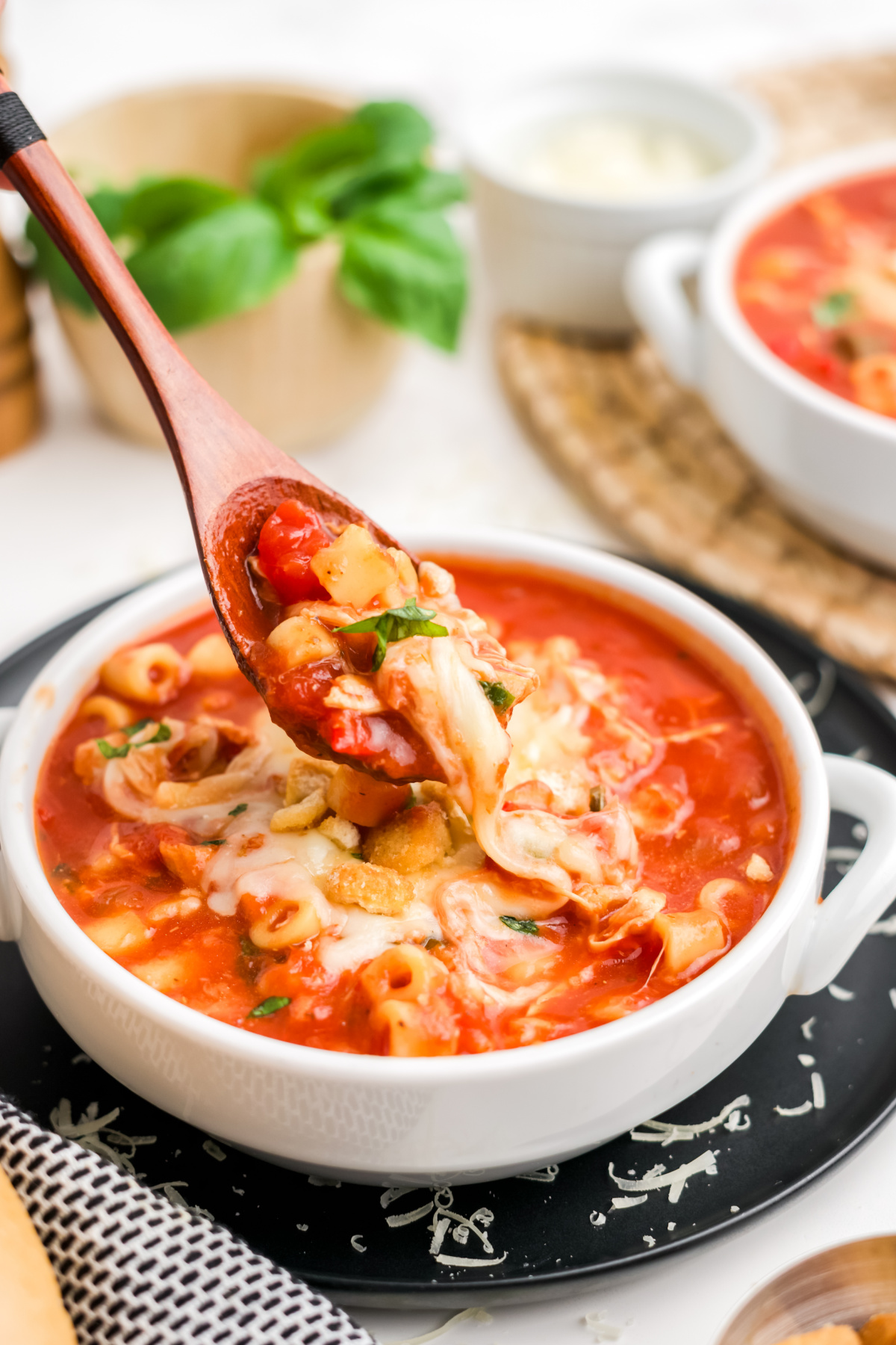 Chicken soup with cheese sliding off of a spoon.