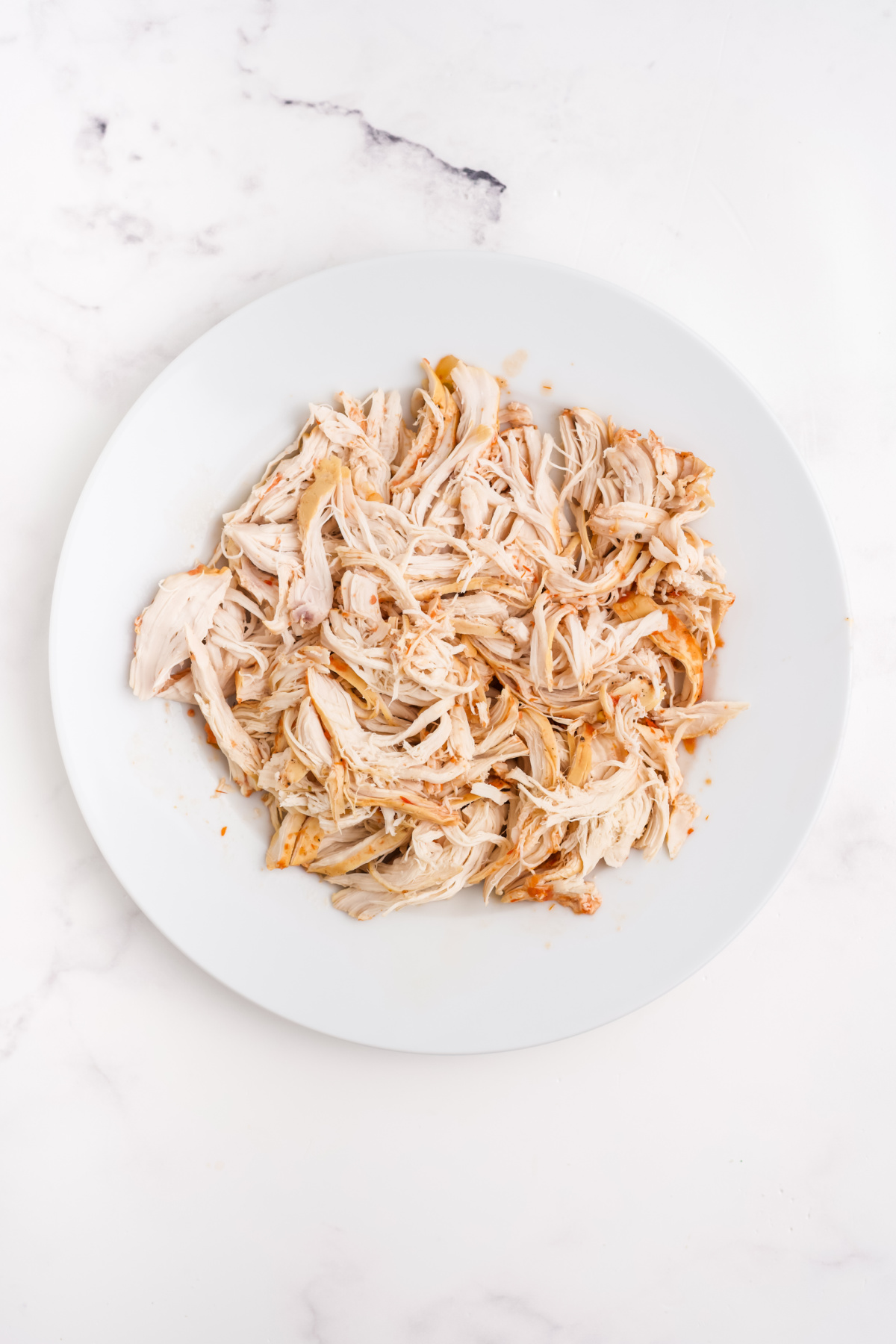 Cooked chicken, shredded on a plate.