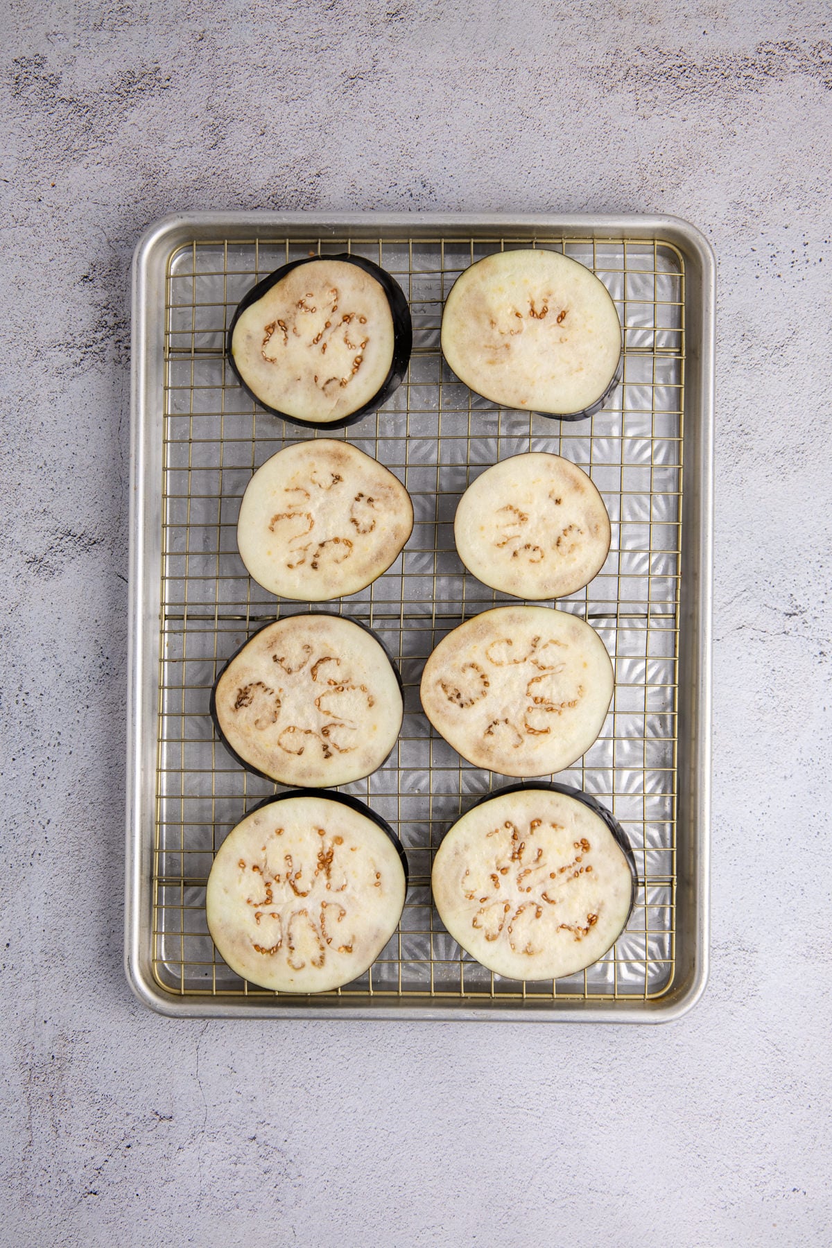 Eggplant slices placed on a wire rack.
