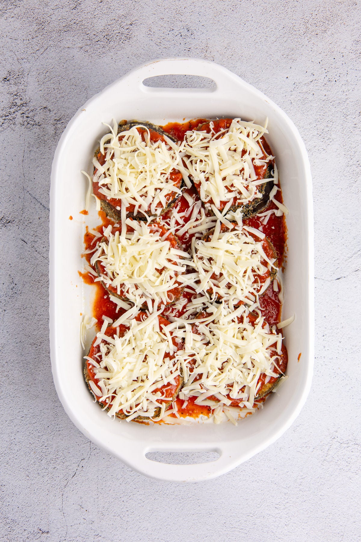 Sauce, eggplant and cheese layered in a casserole dish.