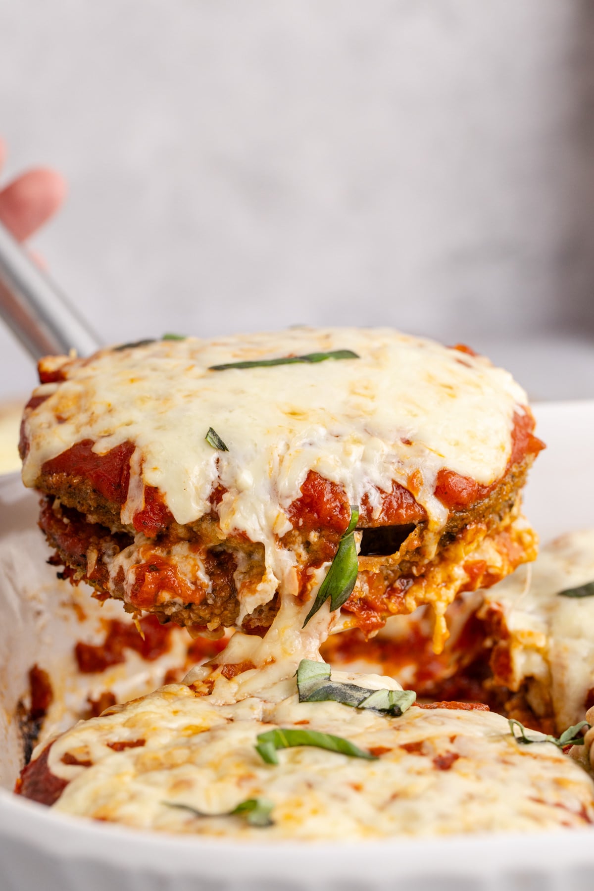 A casserole with eggplant cheese and sauce scooped up with a spatula.