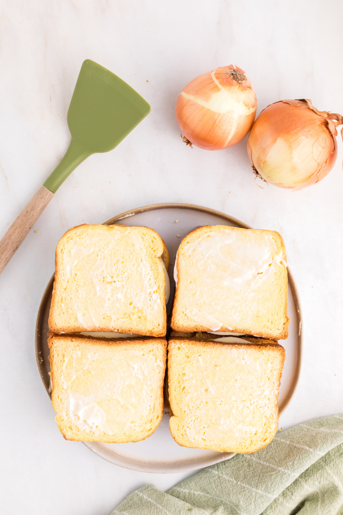 Four grilled cheese sandwiches, cheese added to the second slice of bread.