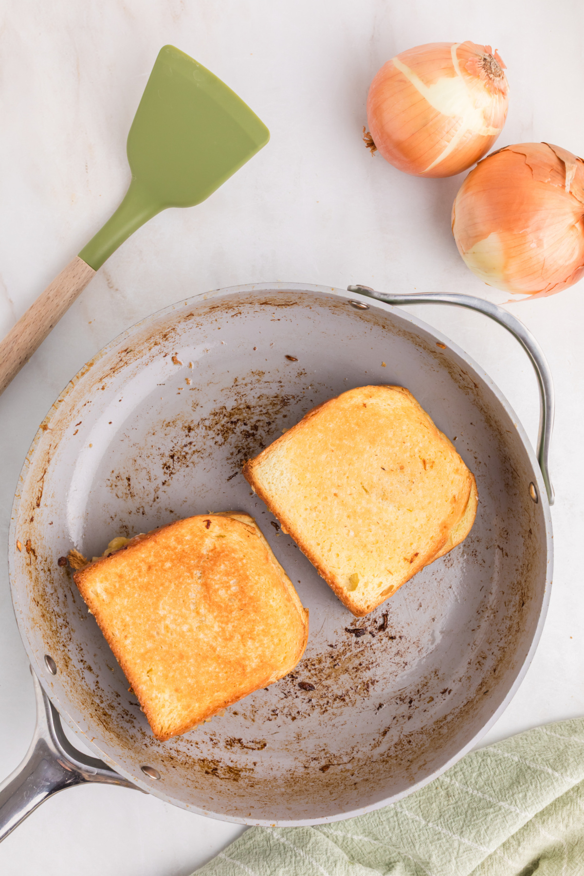 Two grilled cheese sandwiches in a frying pan.