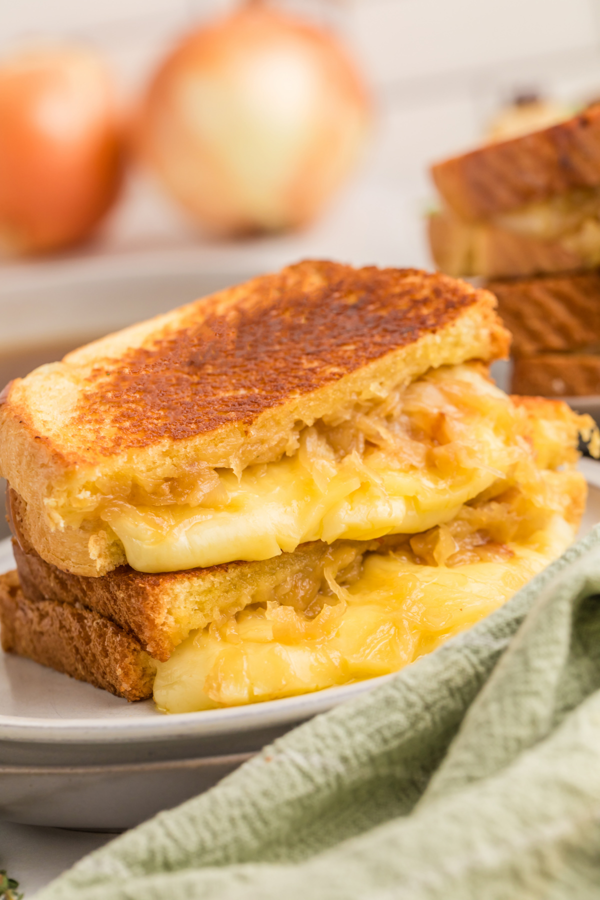 A sandwich with cheese and fried onions in half on a plate.