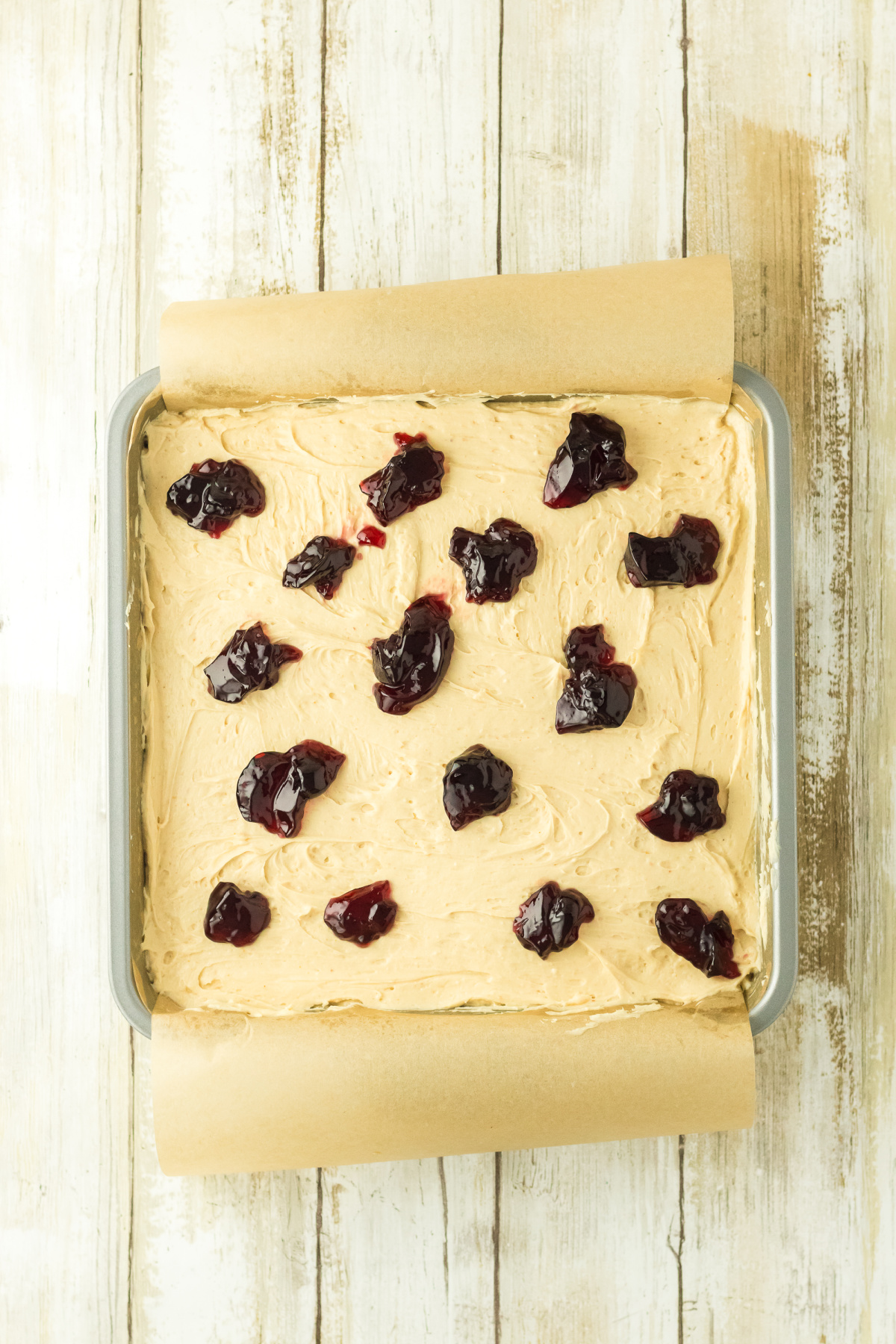 Grape jelly dolloped all over the top of the cheesecake layer.